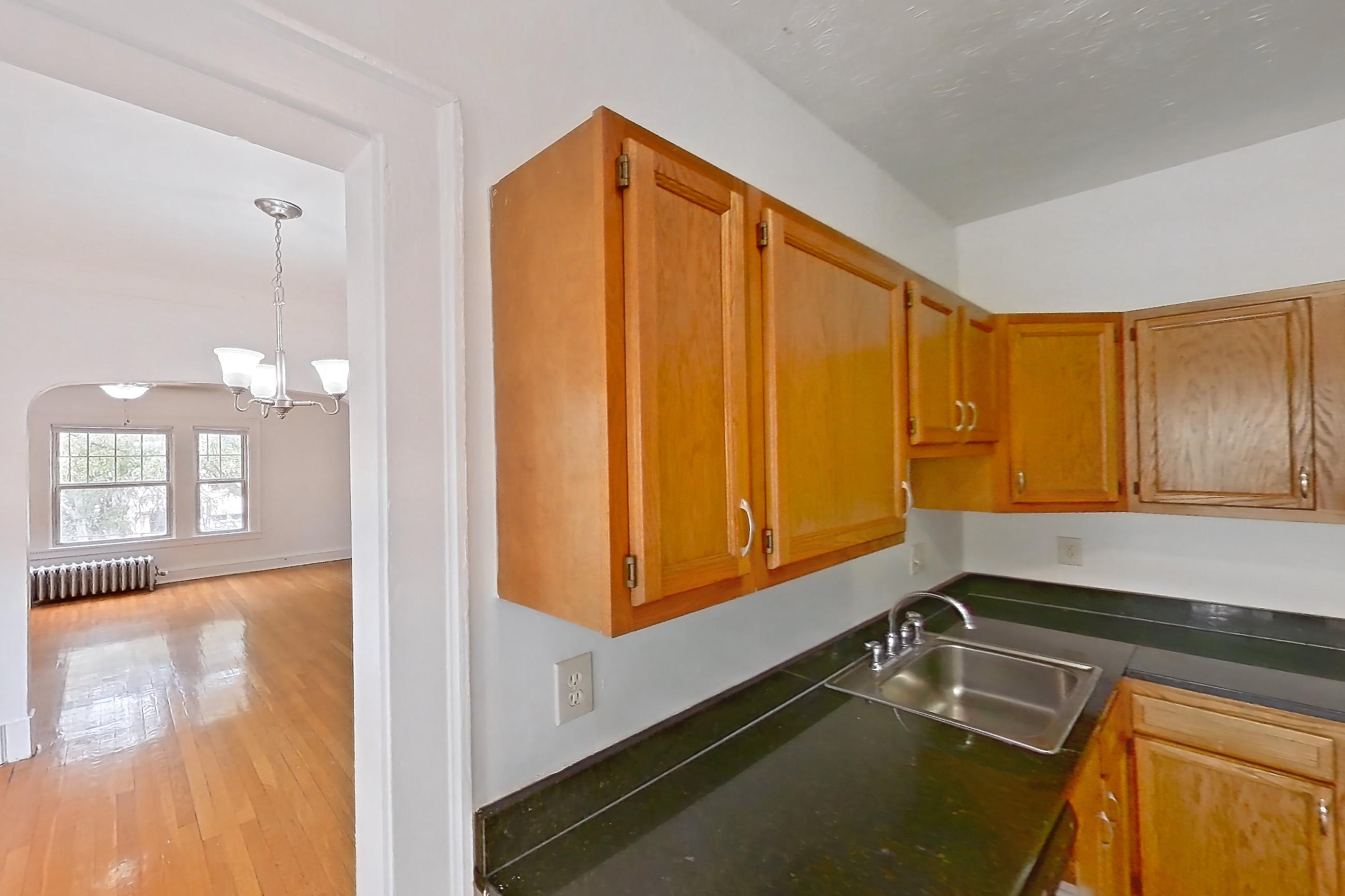 Kitchen with dark countertops, dark stone countertops, dishwasher, gas range, light countertops, light tile flooring, oven/range, refrigerator, and stainless steel appliances, Apartment 95-6 at Integrity Gold Coast