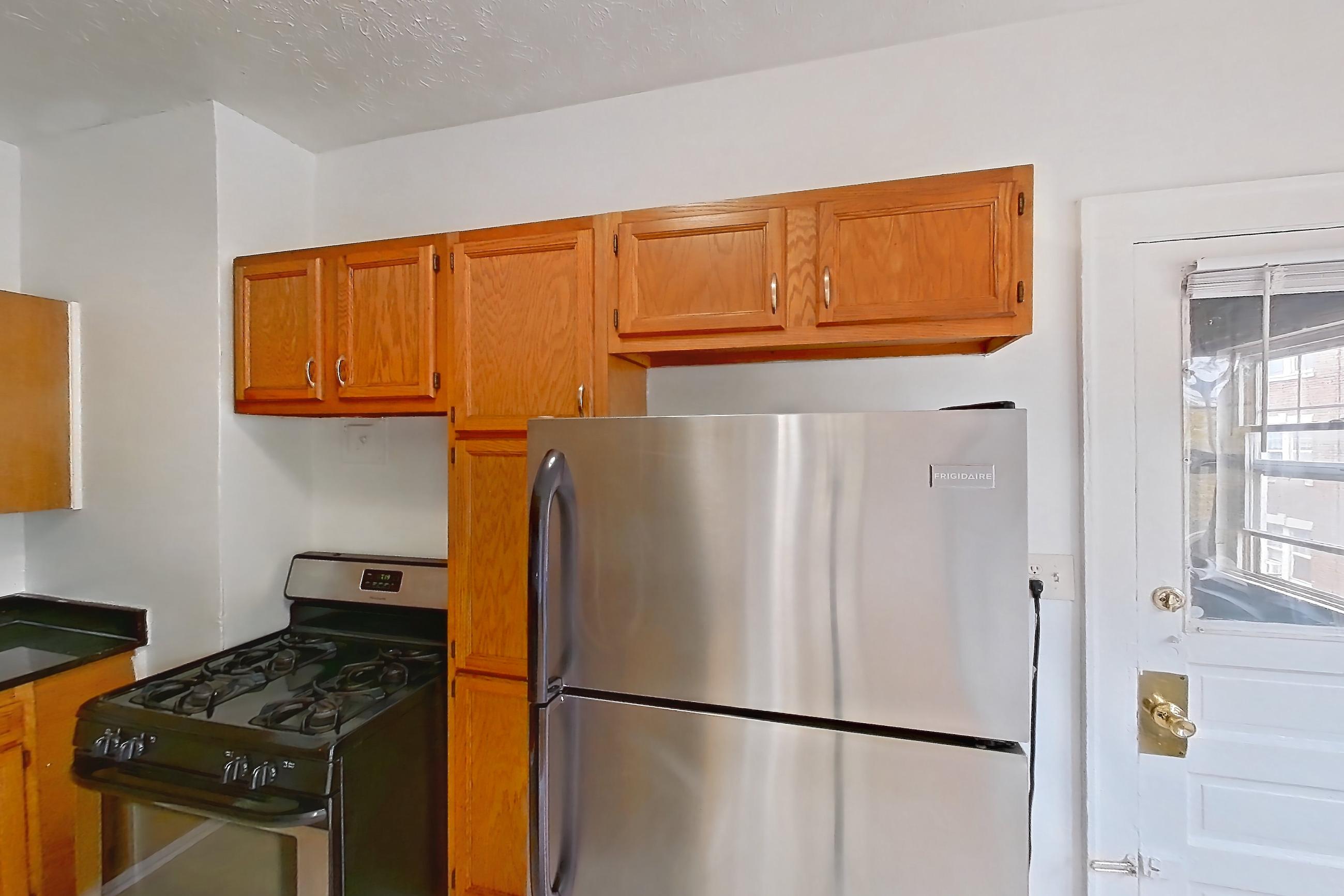 Kitchen with dark countertops, dark stone countertops, dishwasher, gas range, light countertops, light tile flooring, oven/range, refrigerator, and stainless steel appliances, Apartment 95-6 at Integrity Gold Coast