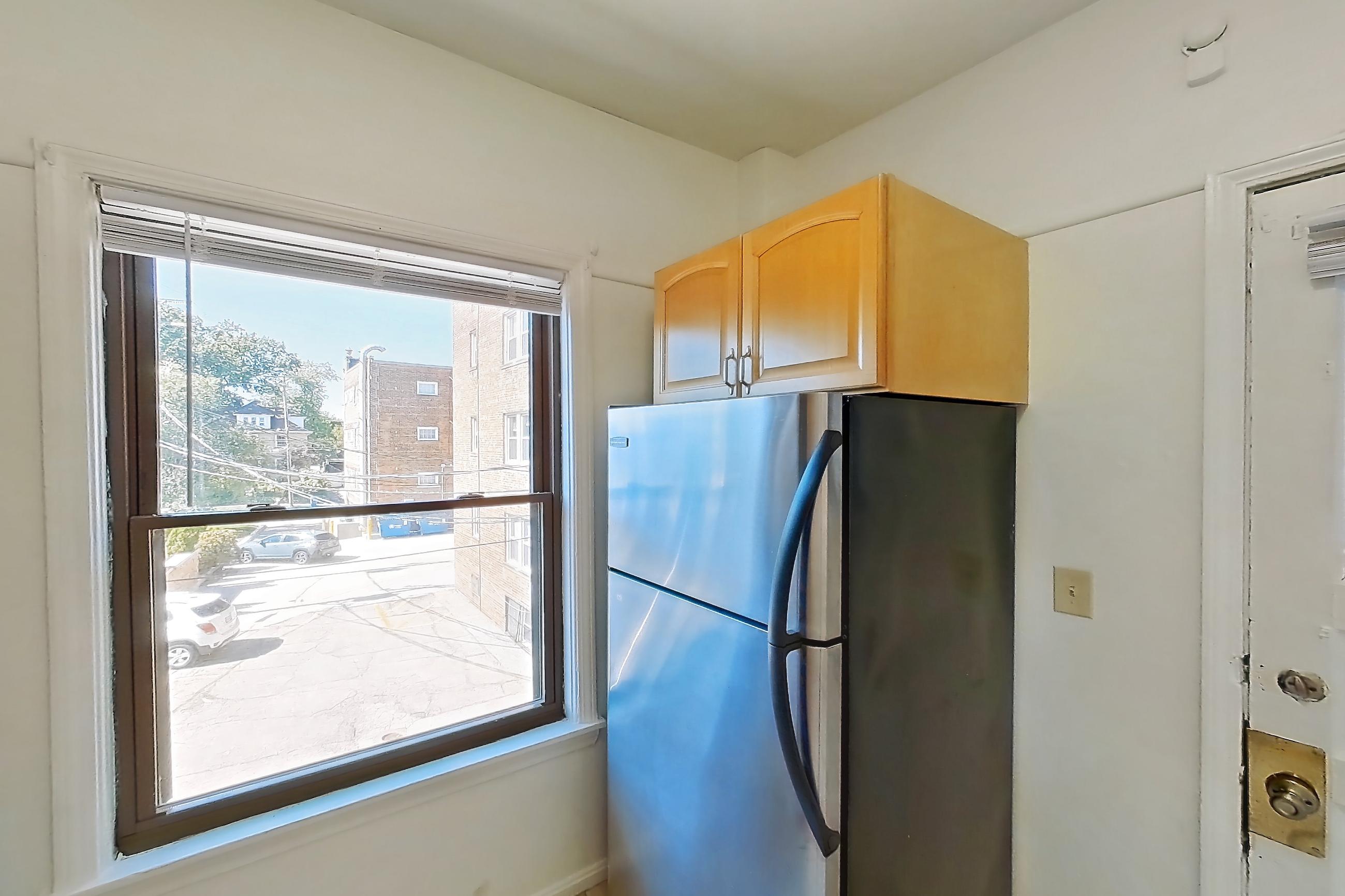 Kitchen with black appliances, dark stone countertops, gas range, light countertops, light tile flooring, microwave, oven/range, refrigerator, and stainless steel appliances, Apartment 13-10 at Integrity Gold Coast
