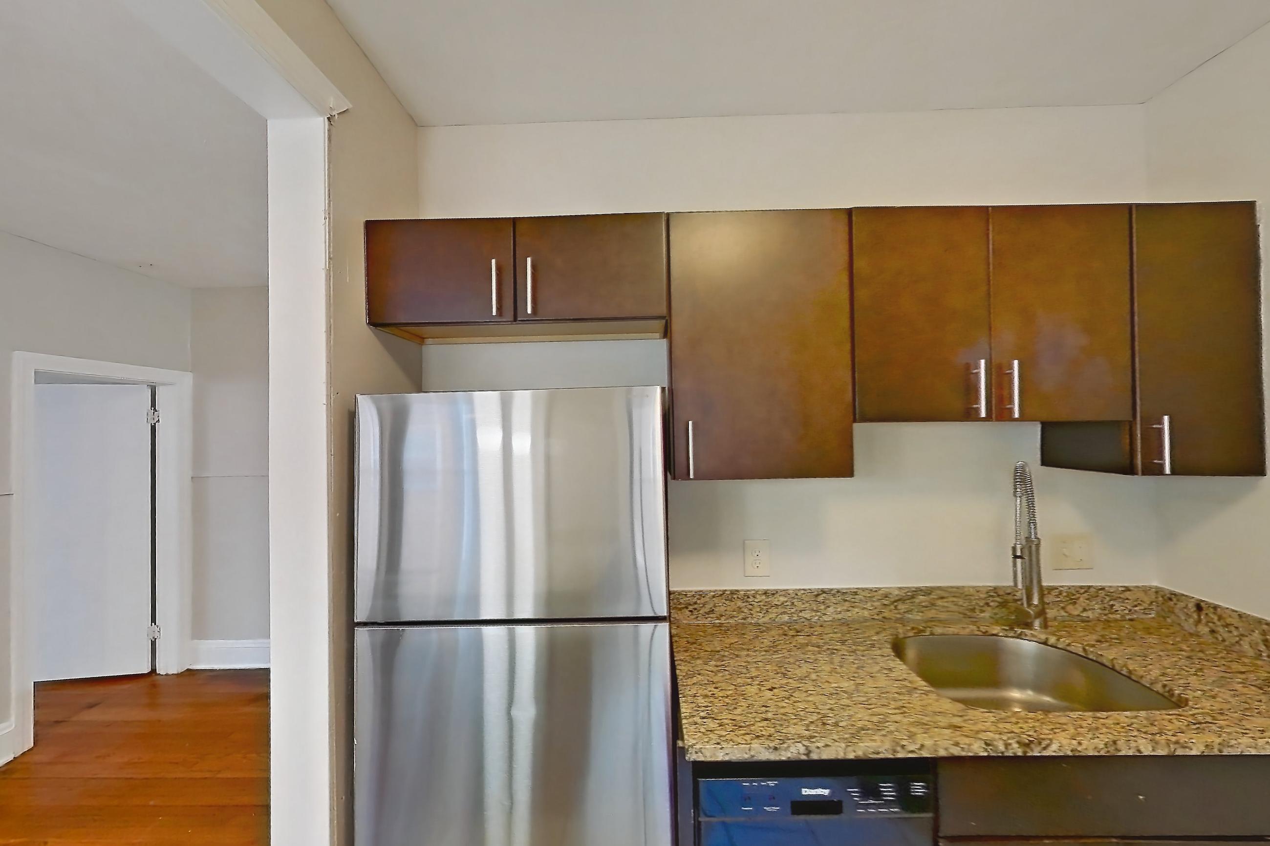 Kitchen with black appliances, dishwasher, gas range, light countertops, light stone countertops, light tile flooring, microwave, oven/range, refrigerator, and stainless steel appliances, Apartment 15-3 at Integrity Gold Coast
