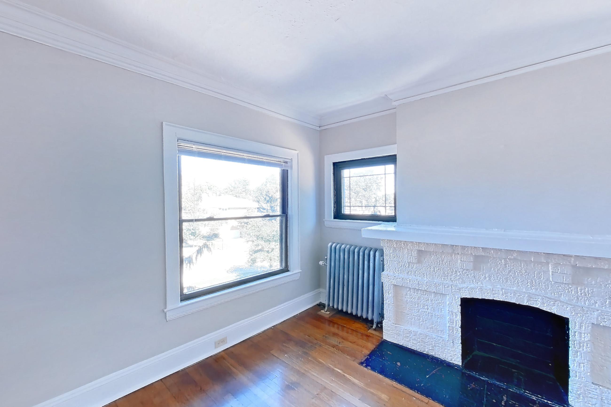 Living room with dark wood-finish flooring, fireplace, radiator heat, and wood-finish flooring, Apartment 15-3 at Integrity Gold Coast
