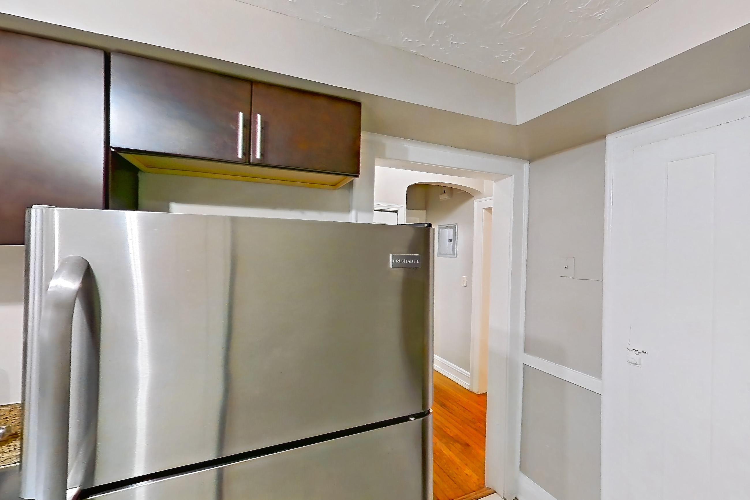 Kitchen with electric range, light countertops, light stone countertops, light tile flooring, oven/range, radiator heat, refrigerator, and stainless steel appliances, Apartment 8 at Integrity Gold Coast