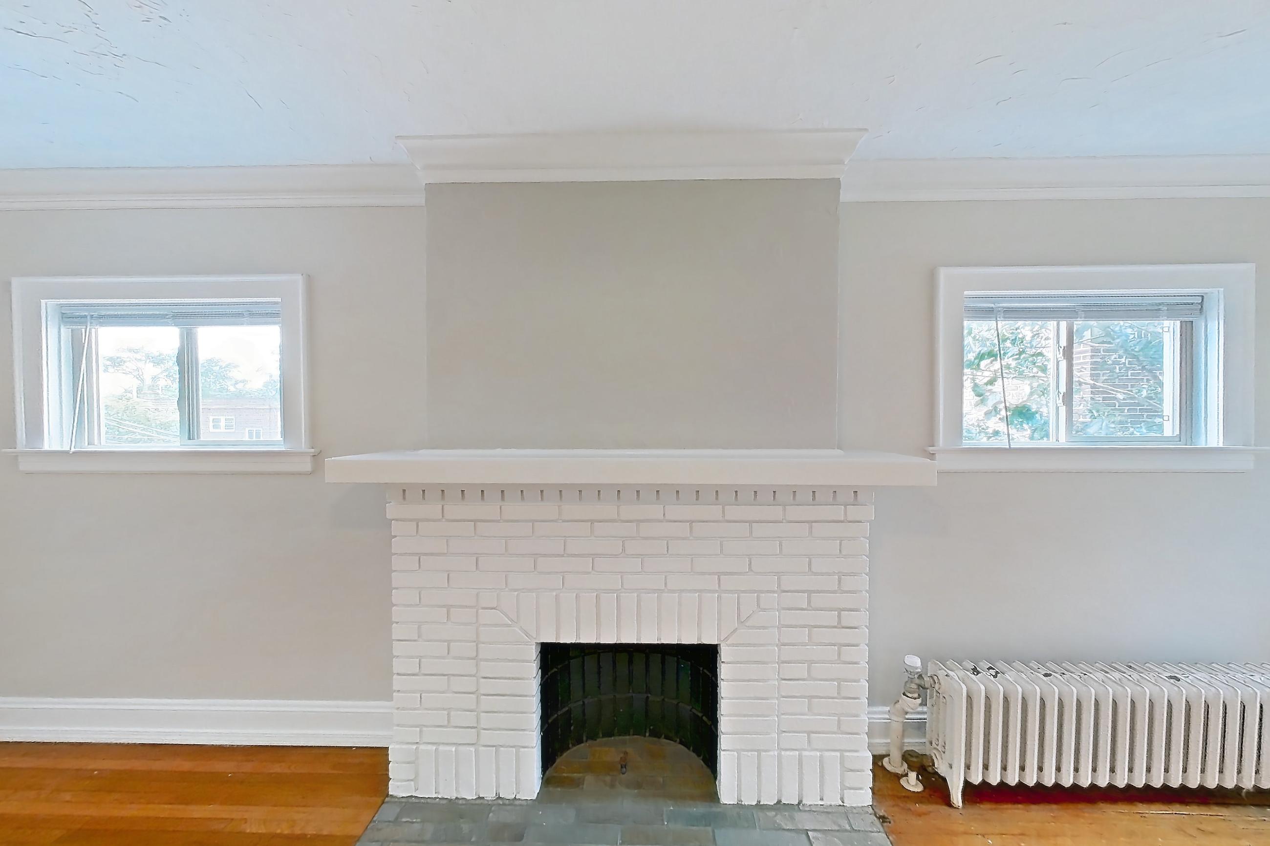 Living room with brick fireplace, fireplace, light wood-finish flooring, and wood-finish flooring, Apartment 8 at Integrity Gold Coast