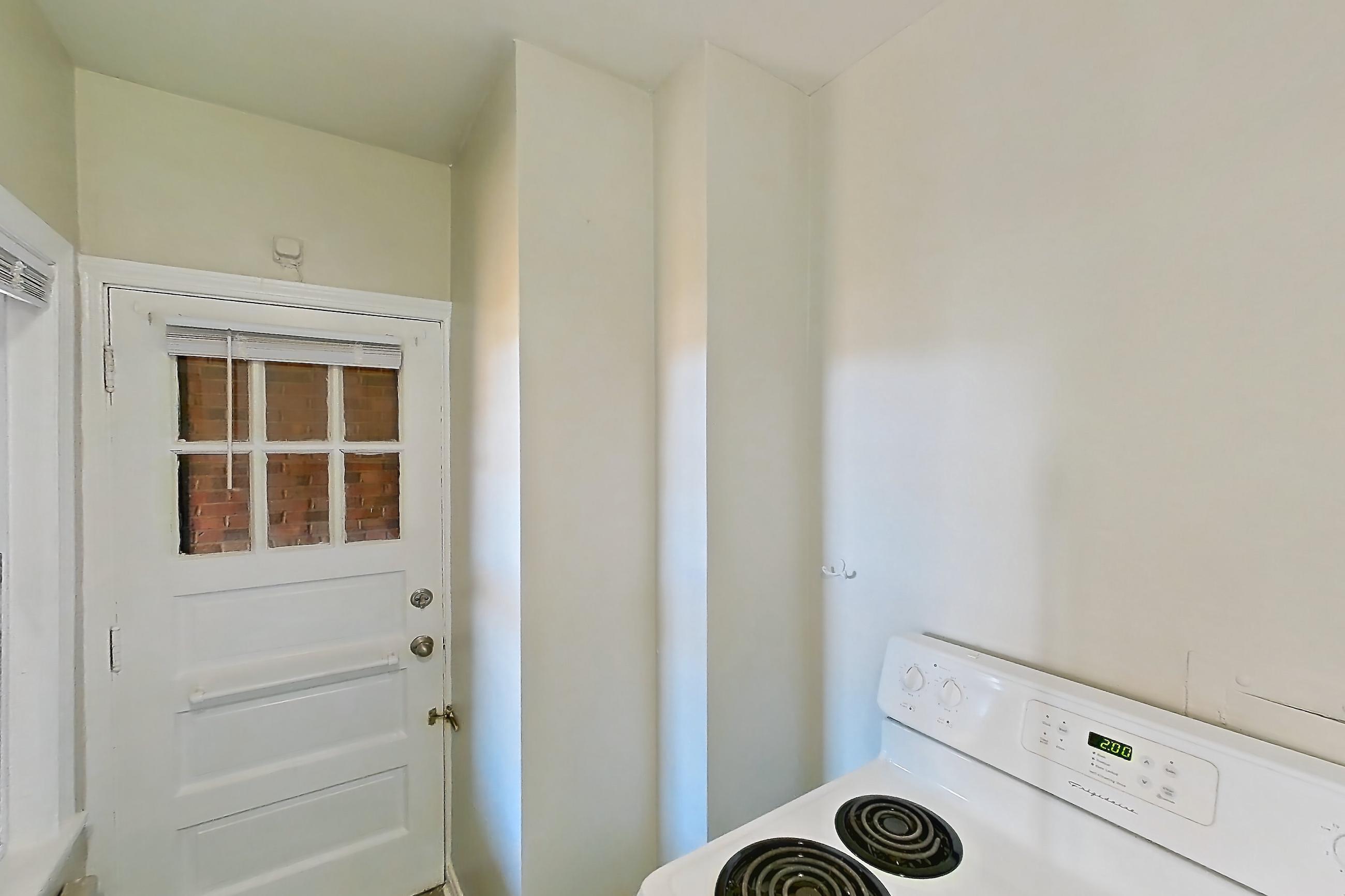 Kitchen with dark countertops, electric range, light wood-finish flooring, oven/range, and white appliances, Apartment 302 at Integrity Gold Coast