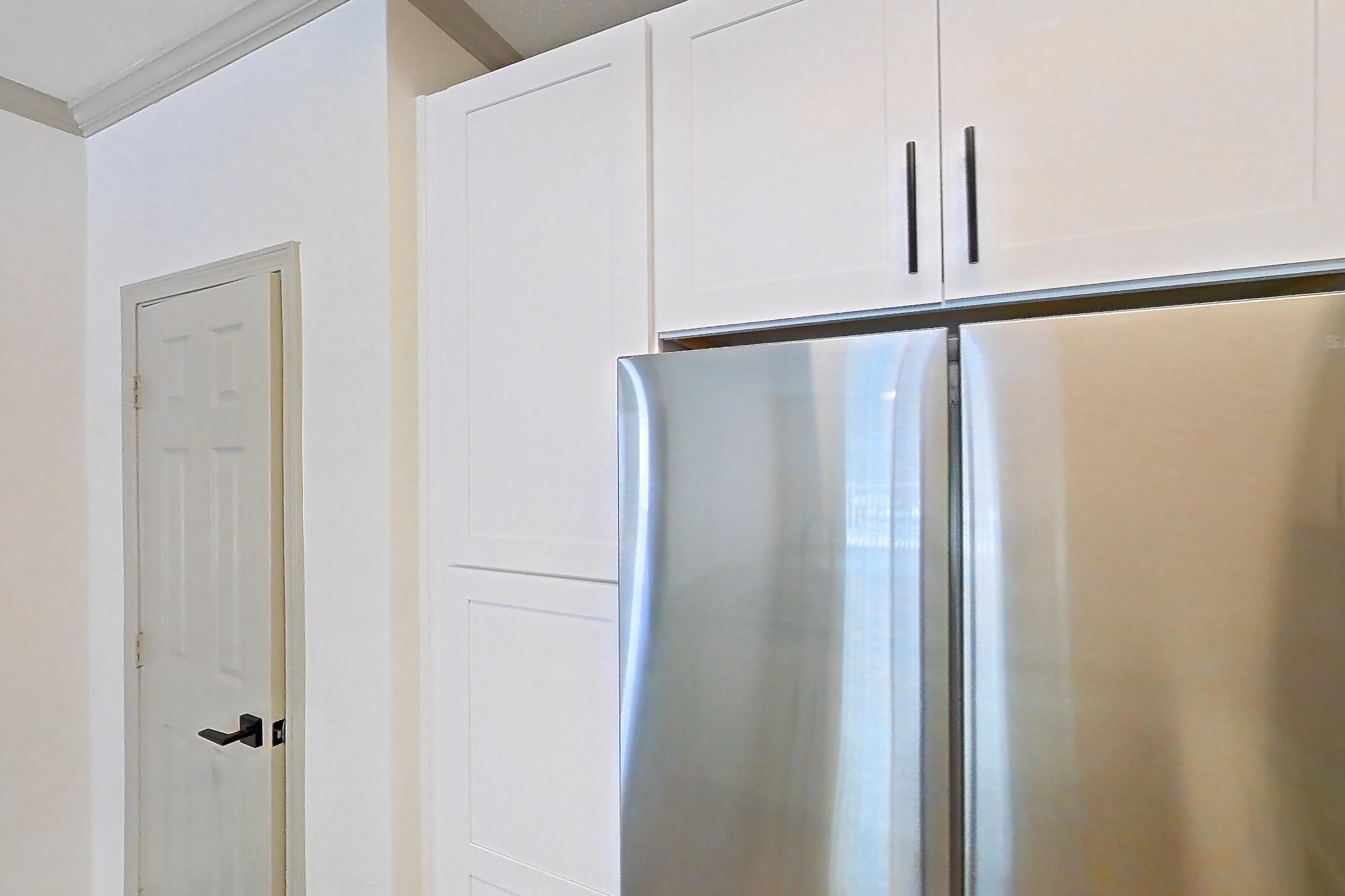 Kitchen with dark stone countertops, dishwasher, electric range, light countertops, light wood-finish flooring, microwave, oven/range, refrigerator, and stainless steel appliances, Apartment 17-205 at Cortland Westminster