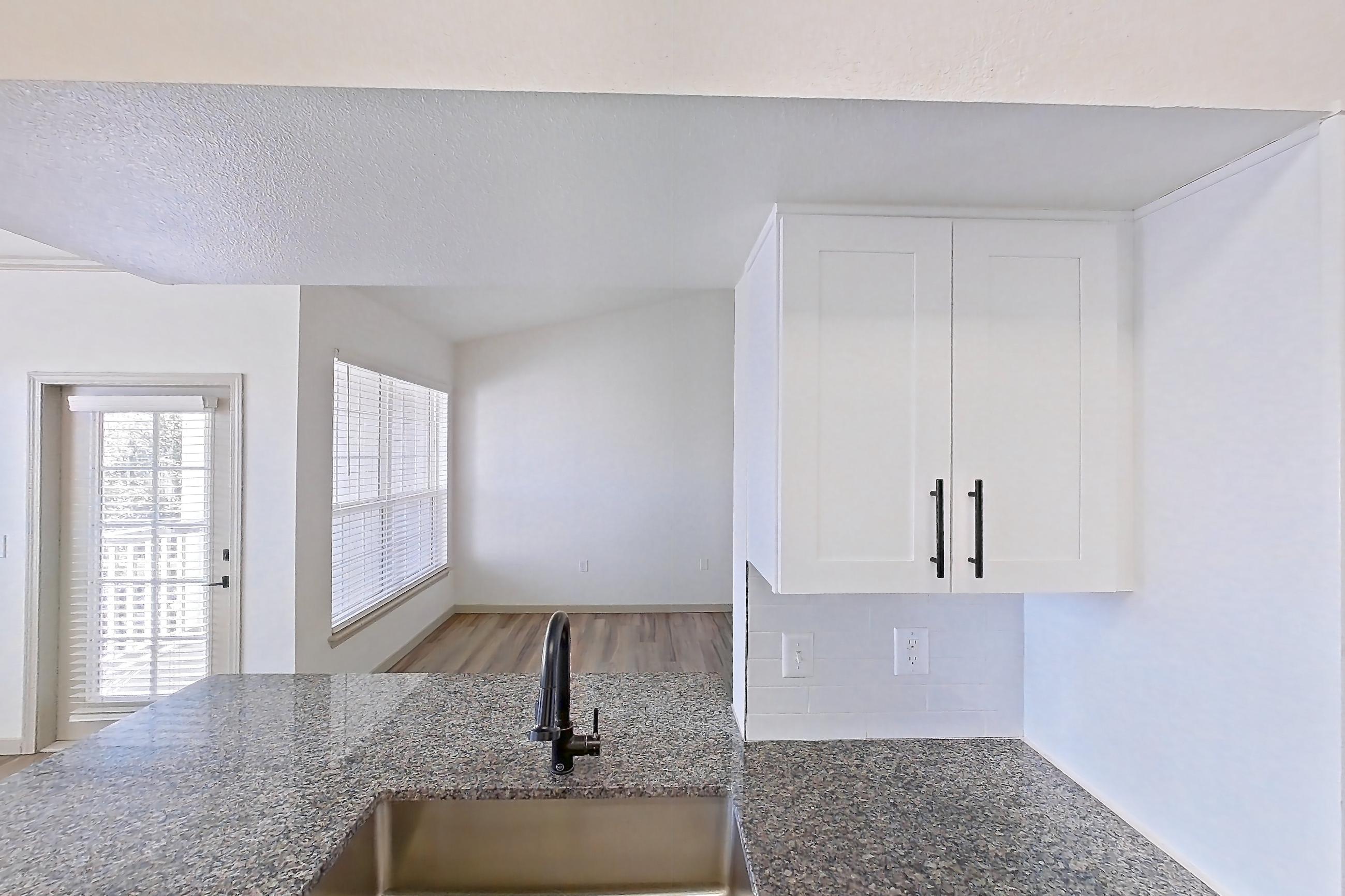 Kitchen with dark stone countertops, dishwasher, electric range, light countertops, light wood-finish flooring, microwave, oven/range, refrigerator, and stainless steel appliances, Apartment 08-302 at Cortland Westminster