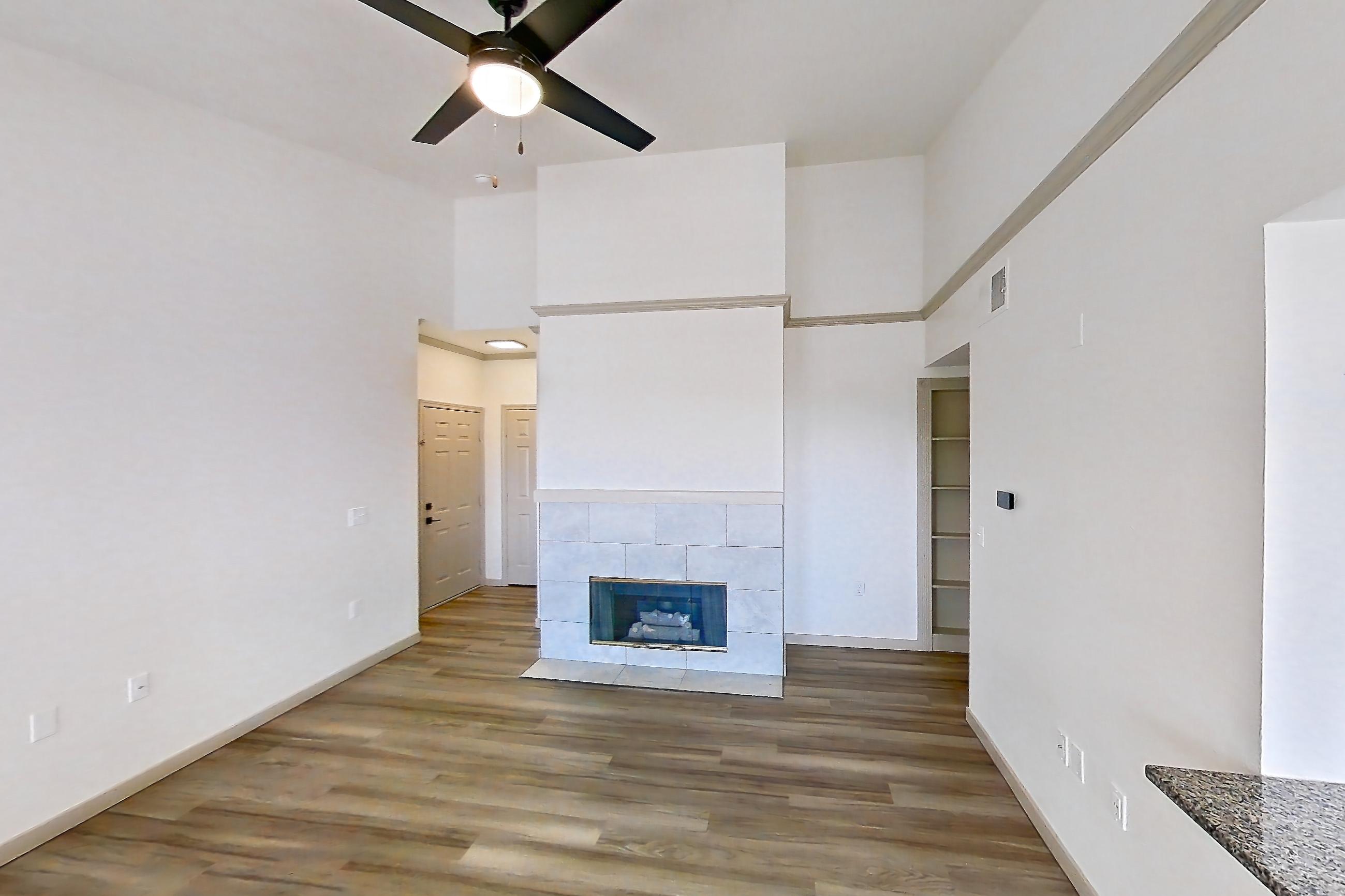 Living space with dark stone countertops, dark wood-finish flooring, electric range, fireplace, light wood-finish flooring, oven/range, refrigerator, stainless steel appliances, and tile fireplace, Apartment 08-302 at Cortland Westminster