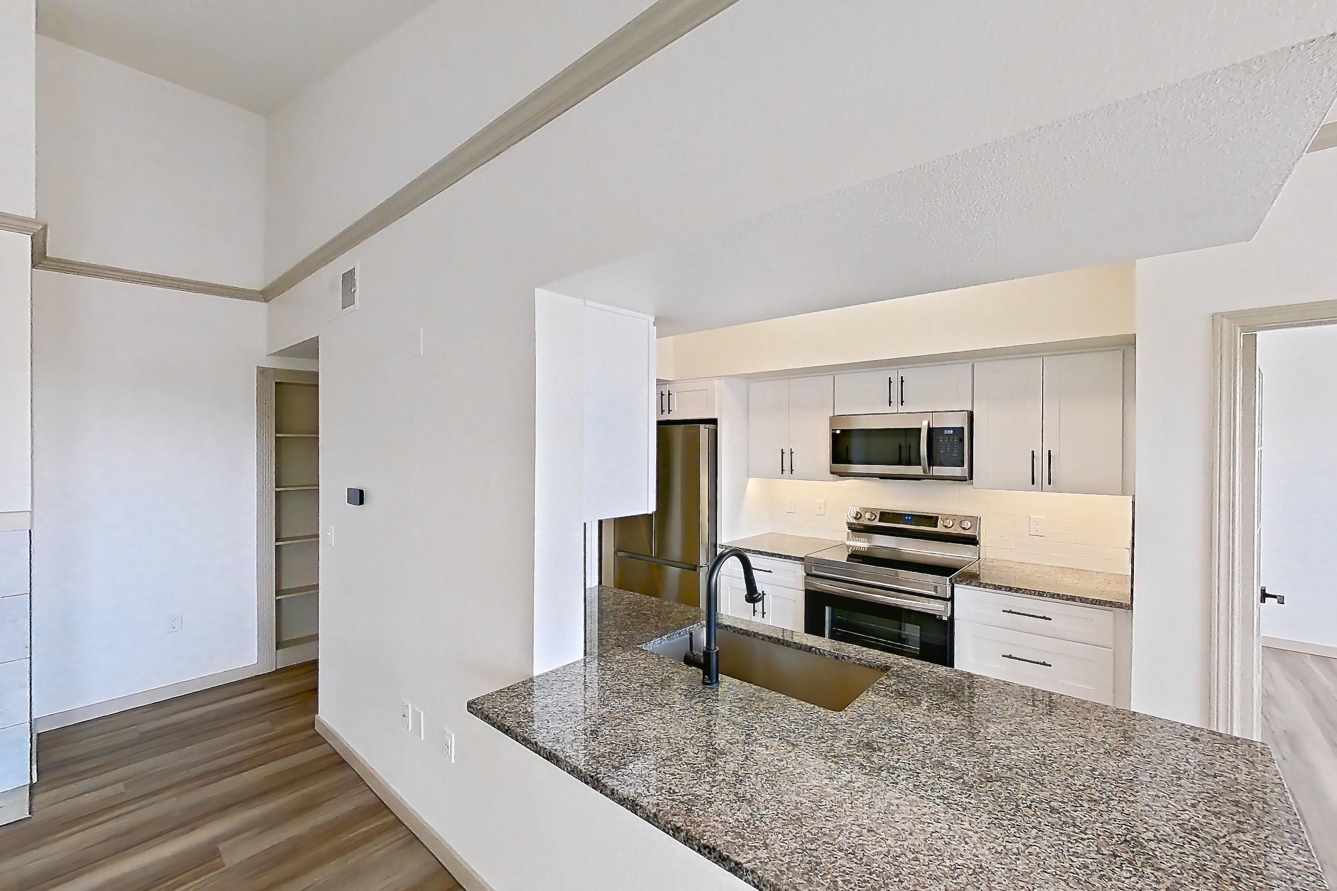 Living space with dark stone countertops, dark wood-finish flooring, electric range, fireplace, light wood-finish flooring, oven/range, refrigerator, stainless steel appliances, and tile fireplace, Apartment 08-302 at Cortland Westminster