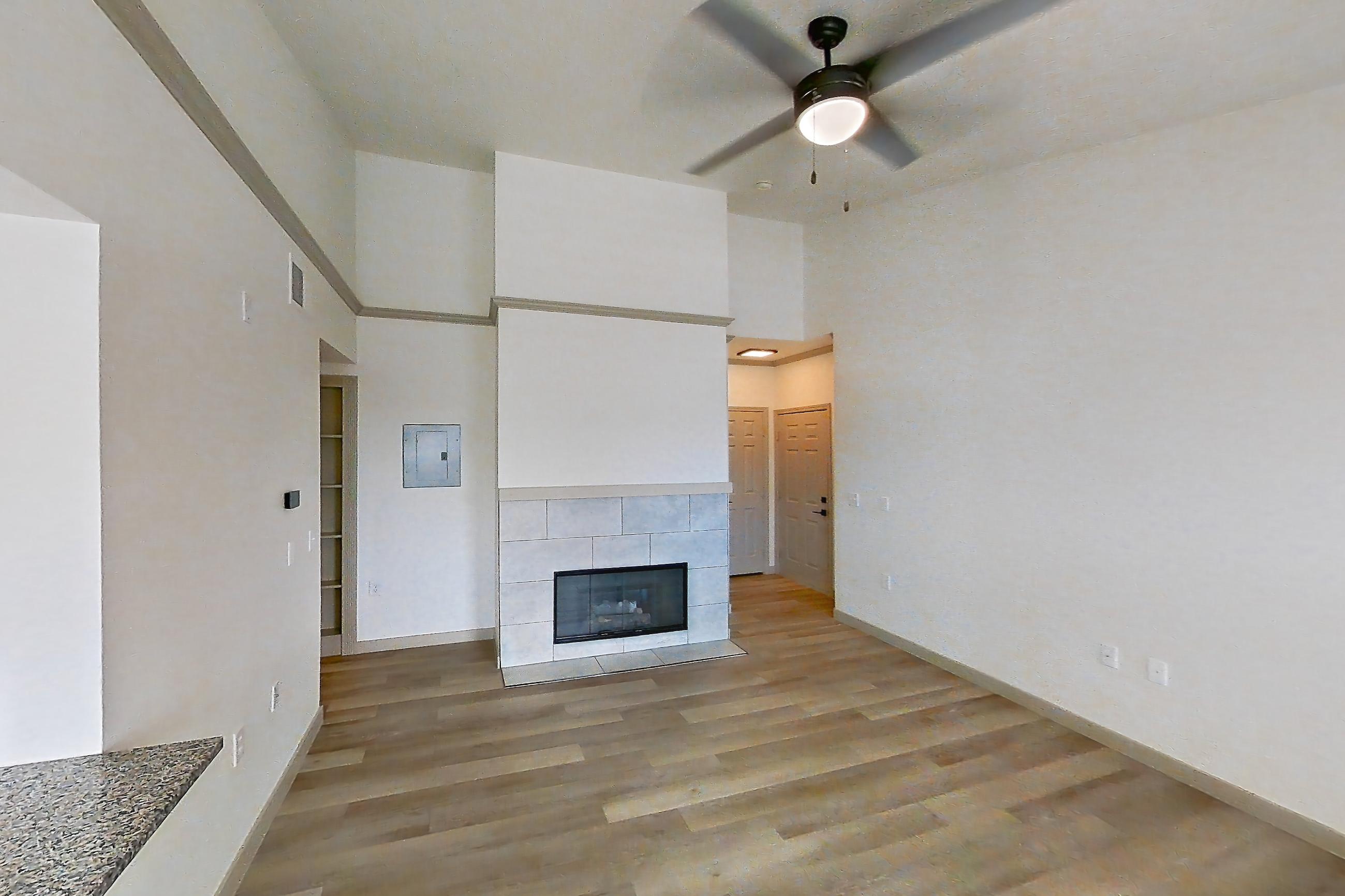 Living space with dark stone countertops, electric range, fireplace, light wood-finish flooring, oven/range, refrigerator, stainless steel appliances, and tile fireplace, Apartment 16-303 at Cortland Westminster