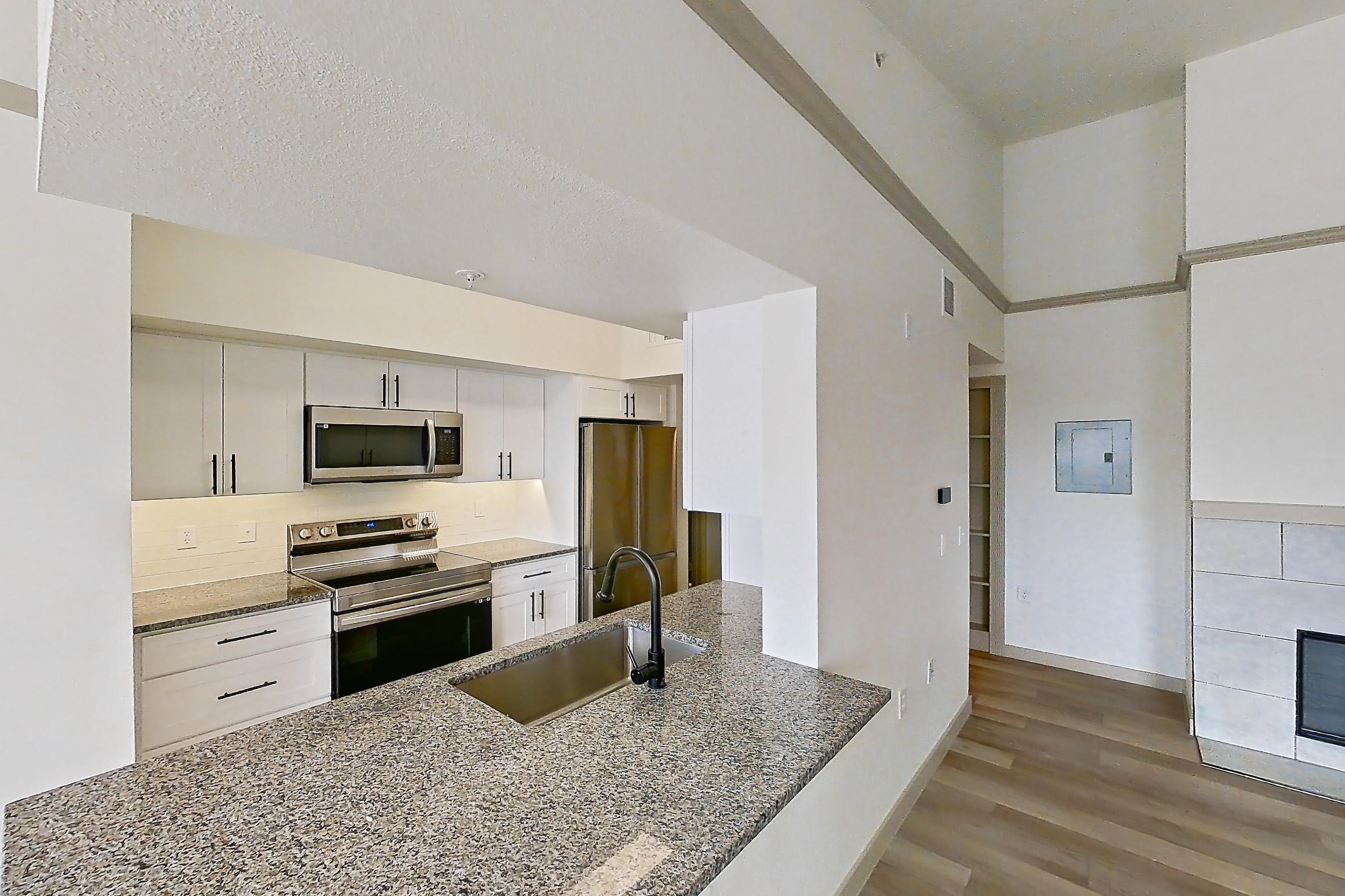 Living space with dark stone countertops, electric range, fireplace, light wood-finish flooring, oven/range, refrigerator, stainless steel appliances, and tile fireplace, Apartment 16-303 at Cortland Westminster