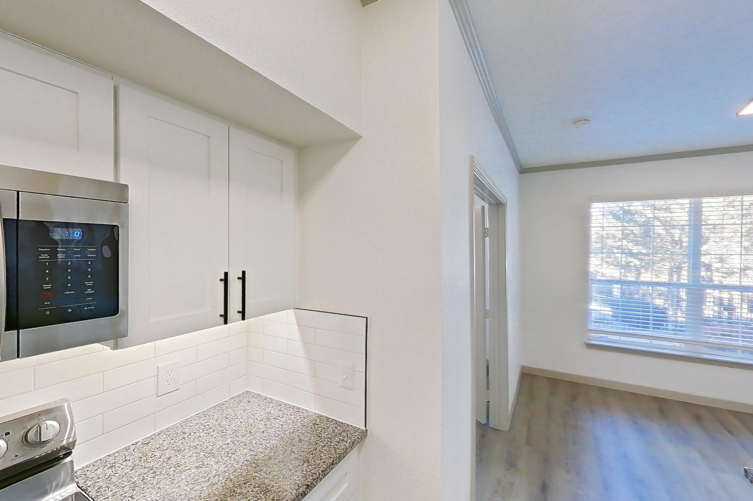Kitchen with dishwasher, electric range, light countertops, light stone countertops, light wood-finish flooring, microwave, oven/range, refrigerator, and stainless steel appliances, Apartment 20-106 at Cortland Westminster