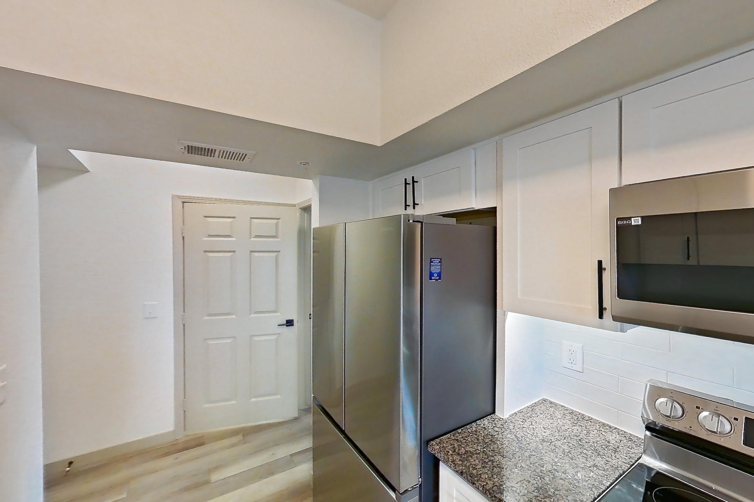 Kitchen with dark stone countertops, dishwasher, electric range, light wood-finish flooring, microwave, oven/range, refrigerator, and stainless steel appliances, Apartment 21-205 at Cortland Westminster