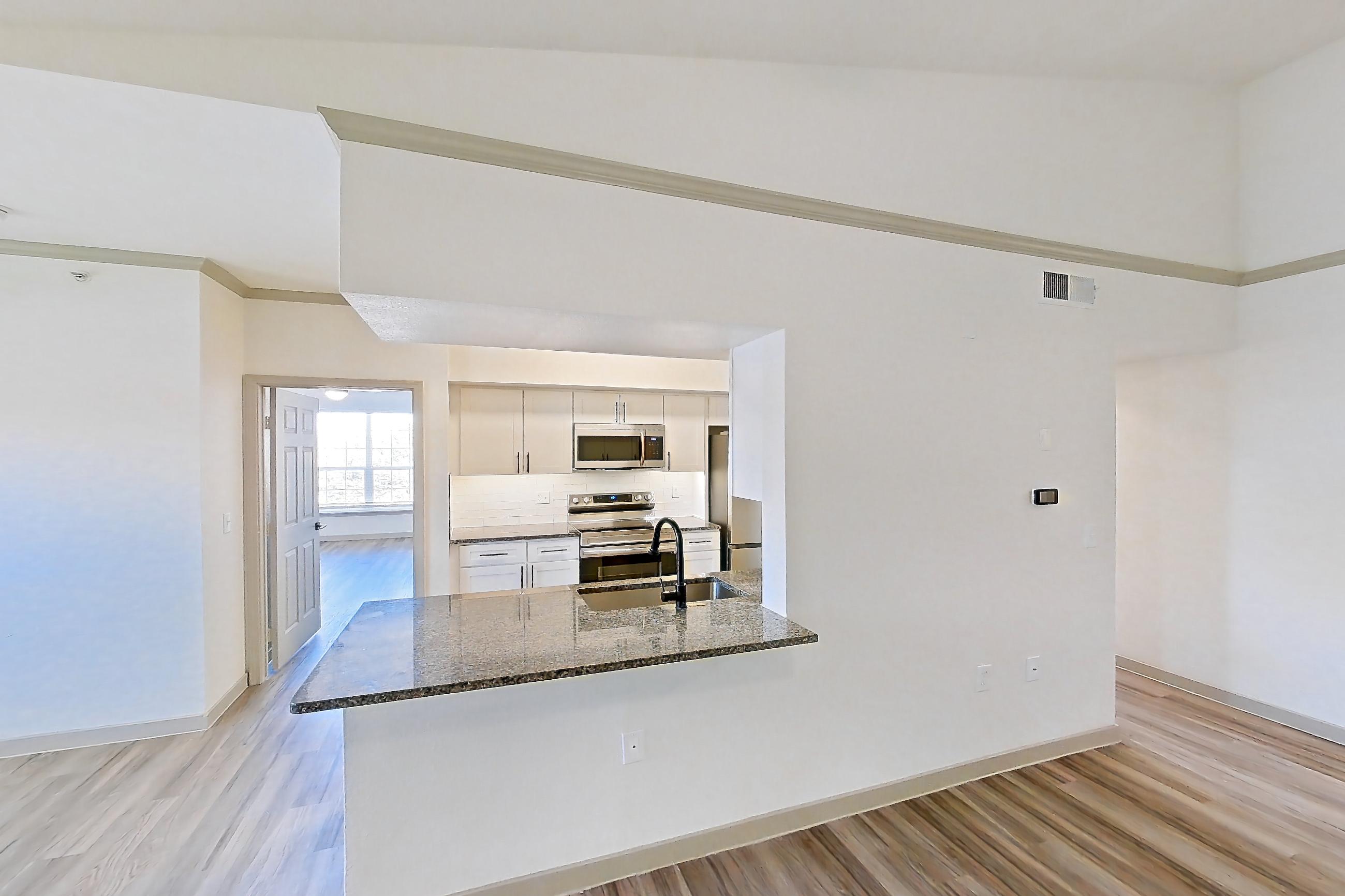 Living space with dark stone countertops, electric range, kitchen island, light wood-finish flooring, oven/range, range hood, refrigerator, and stainless steel appliances, Apartment 22-204 at Cortland Westminster