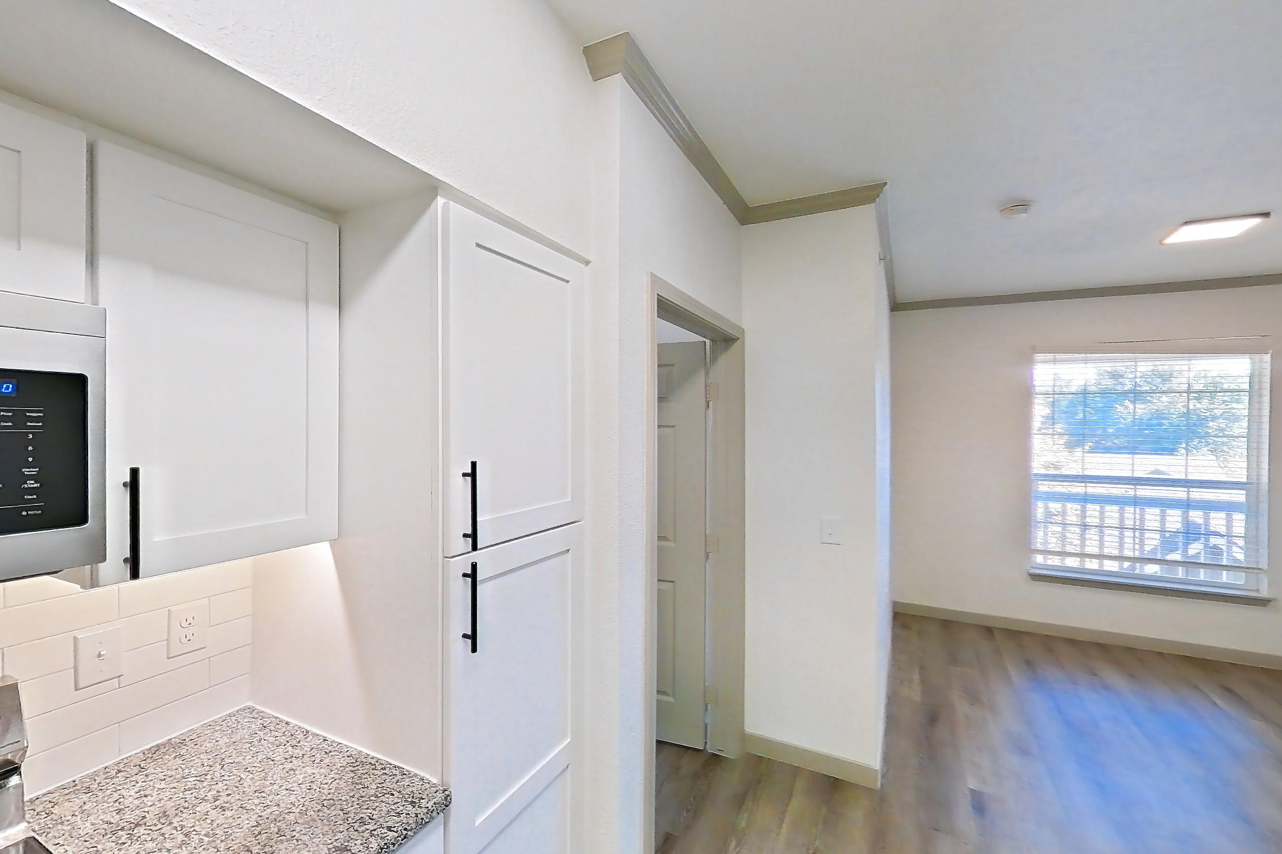 Kitchen with dishwasher, electric range, light stone countertops, light wood-finish flooring, microwave, oven/range, refrigerator, and stainless steel appliances, Apartment 23-201 at Cortland Westminster