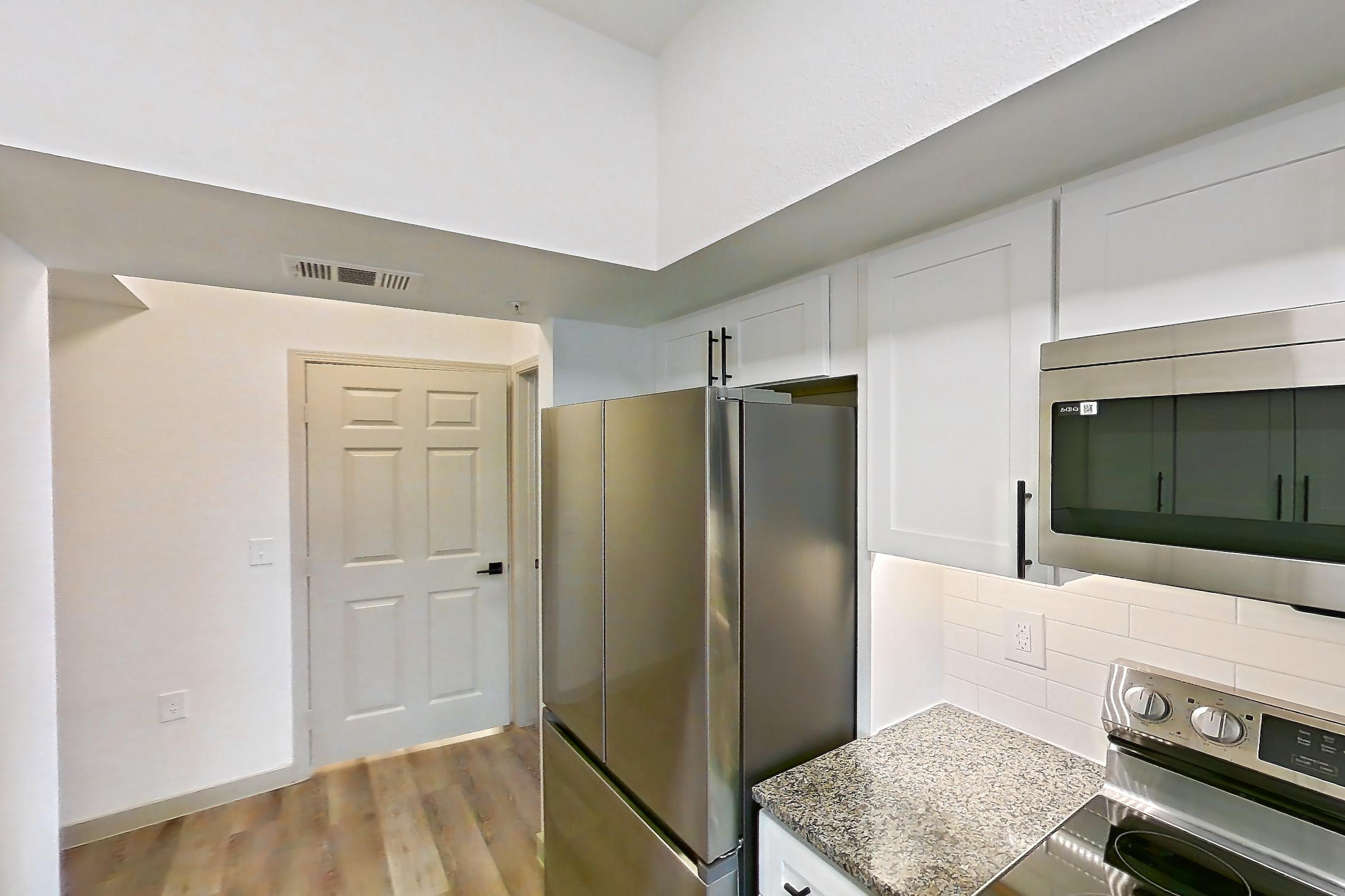 Kitchen with dishwasher, electric range, light stone countertops, light wood-finish flooring, microwave, oven/range, refrigerator, and stainless steel appliances, Apartment 23-201 at Cortland Westminster