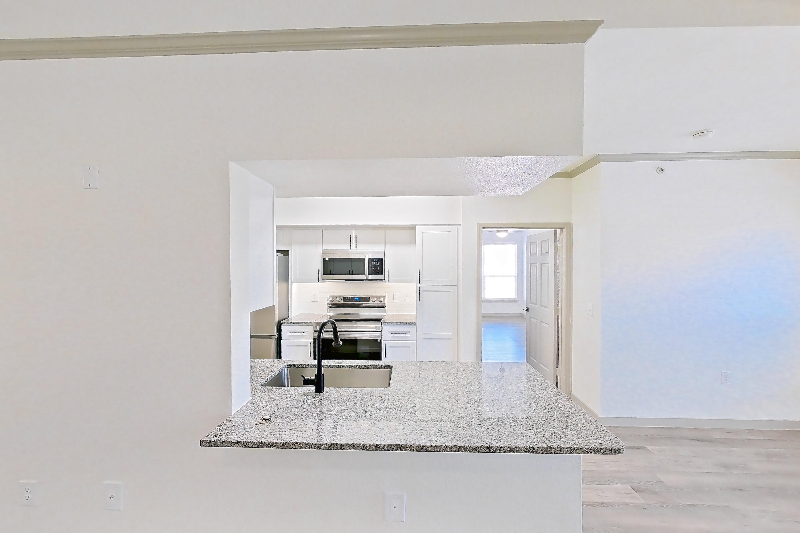 Living space with electric range, light stone countertops, light wood-finish flooring, oven/range, refrigerator, and stainless steel appliances, Apartment 23-201 at Cortland Westminster