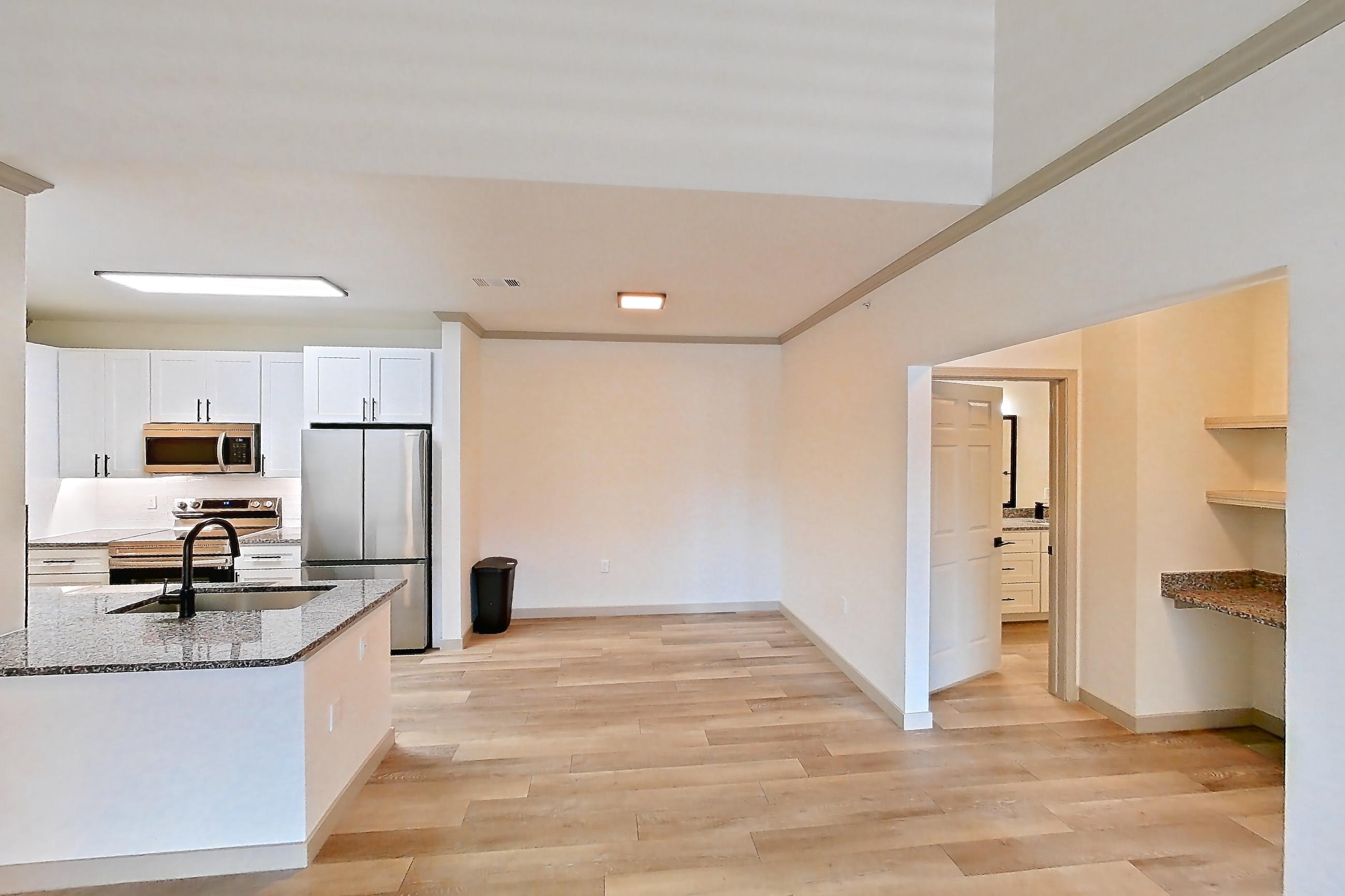 Living space with dark stone countertops, electric range, light wood-finish flooring, oven/range, refrigerator, and stainless steel appliances, Apartment 04-302 at Cortland Westminster