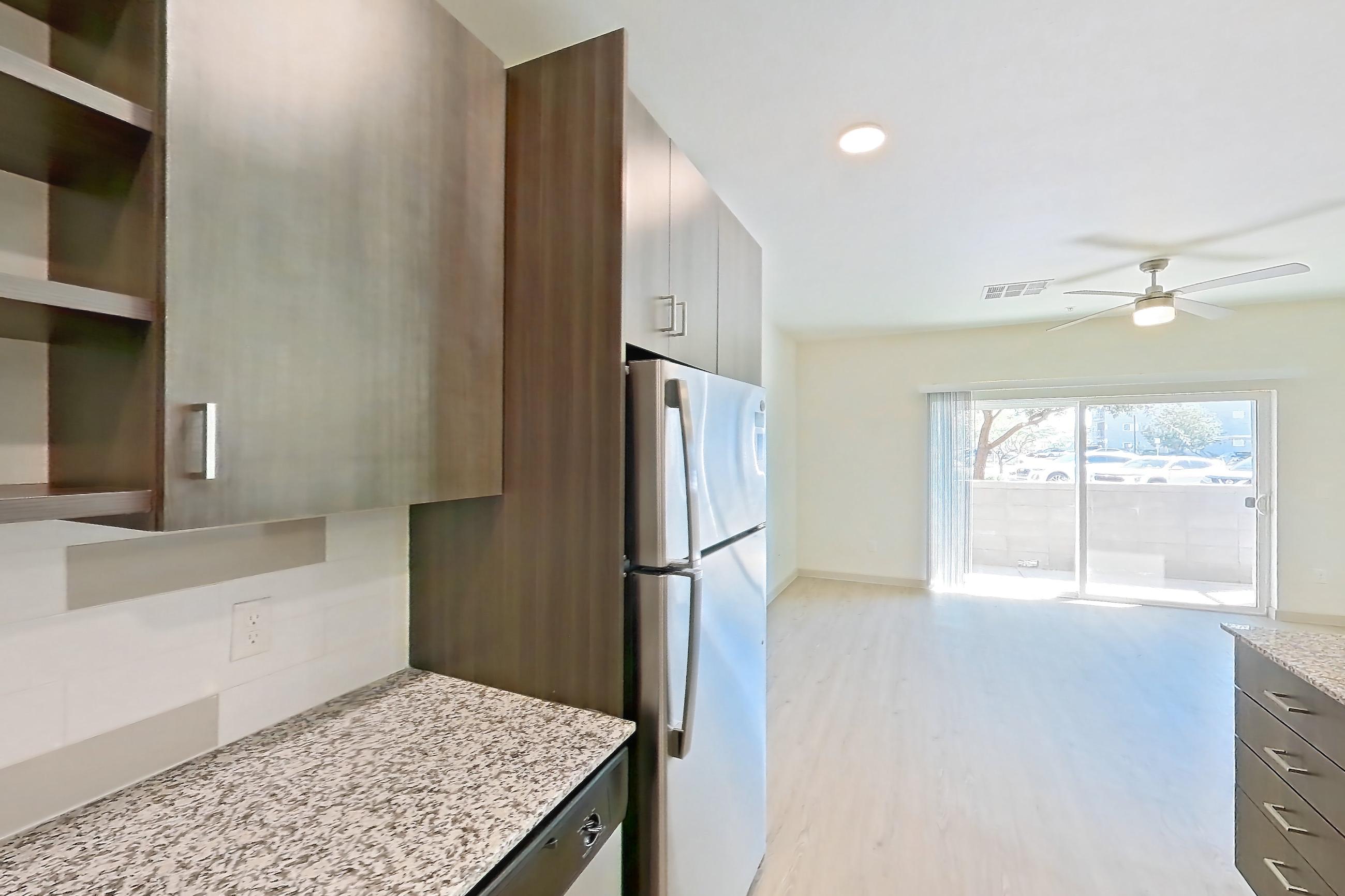 Kitchen with dishwasher, electric range, light stone countertops, light wood-finish flooring, oven/range, refrigerator, and stainless steel appliances, Apartment 1015 at Cortland at P83