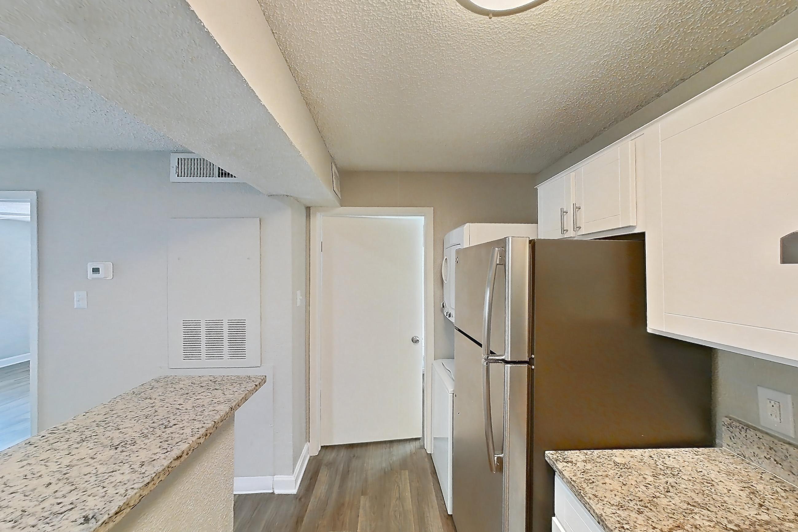 Kitchen with dishwasher, electric range, light countertops, light stone countertops, light wood-finish flooring, oven/range, and stainless steel appliances, Apartment 2103 at Cortland at the Hammocks