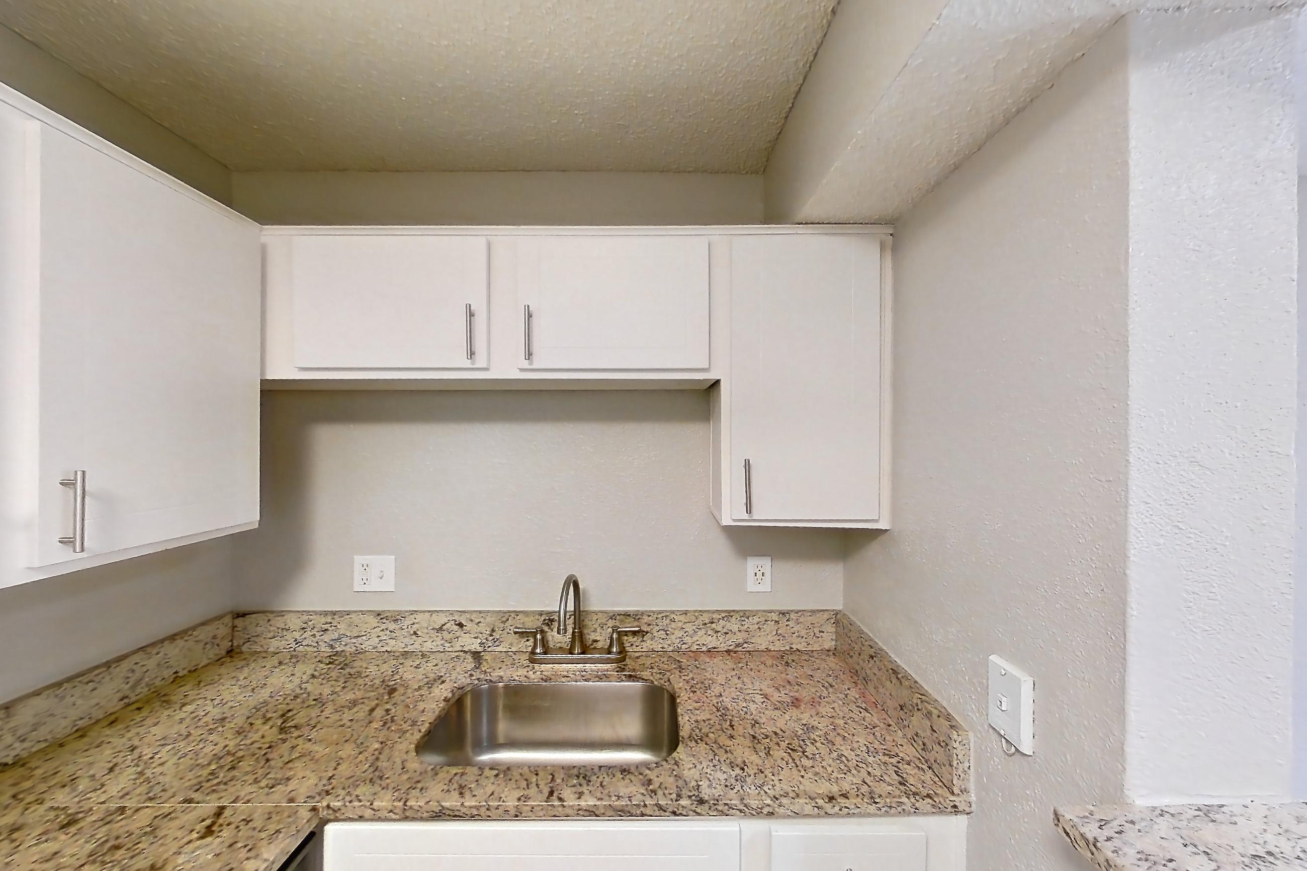 Kitchen with dark wood-finish flooring, dishwasher, electric range, light countertops, light stone countertops, oven/range, refrigerator, and stainless steel appliances, Apartment 2305 at Cortland at the Hammocks