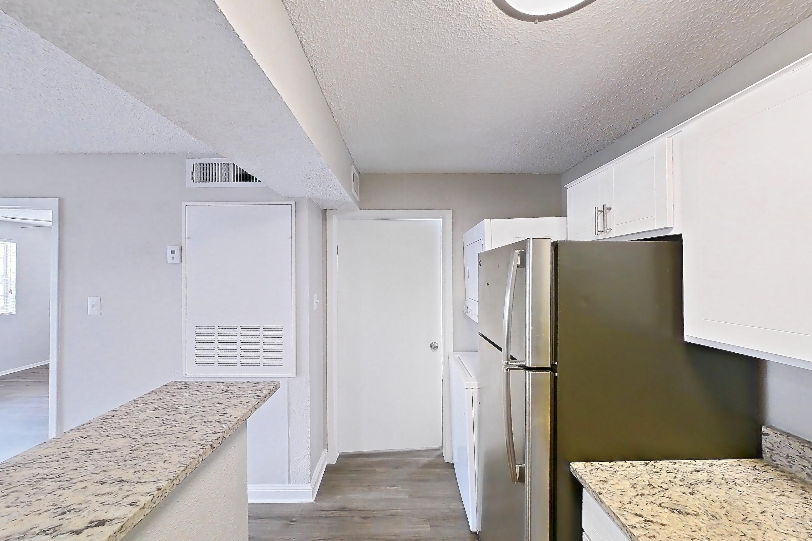 Kitchen with dark wood-finish flooring, dishwasher, electric range, light countertops, light stone countertops, oven/range, refrigerator, and stainless steel appliances, Apartment 2305 at Cortland at the Hammocks