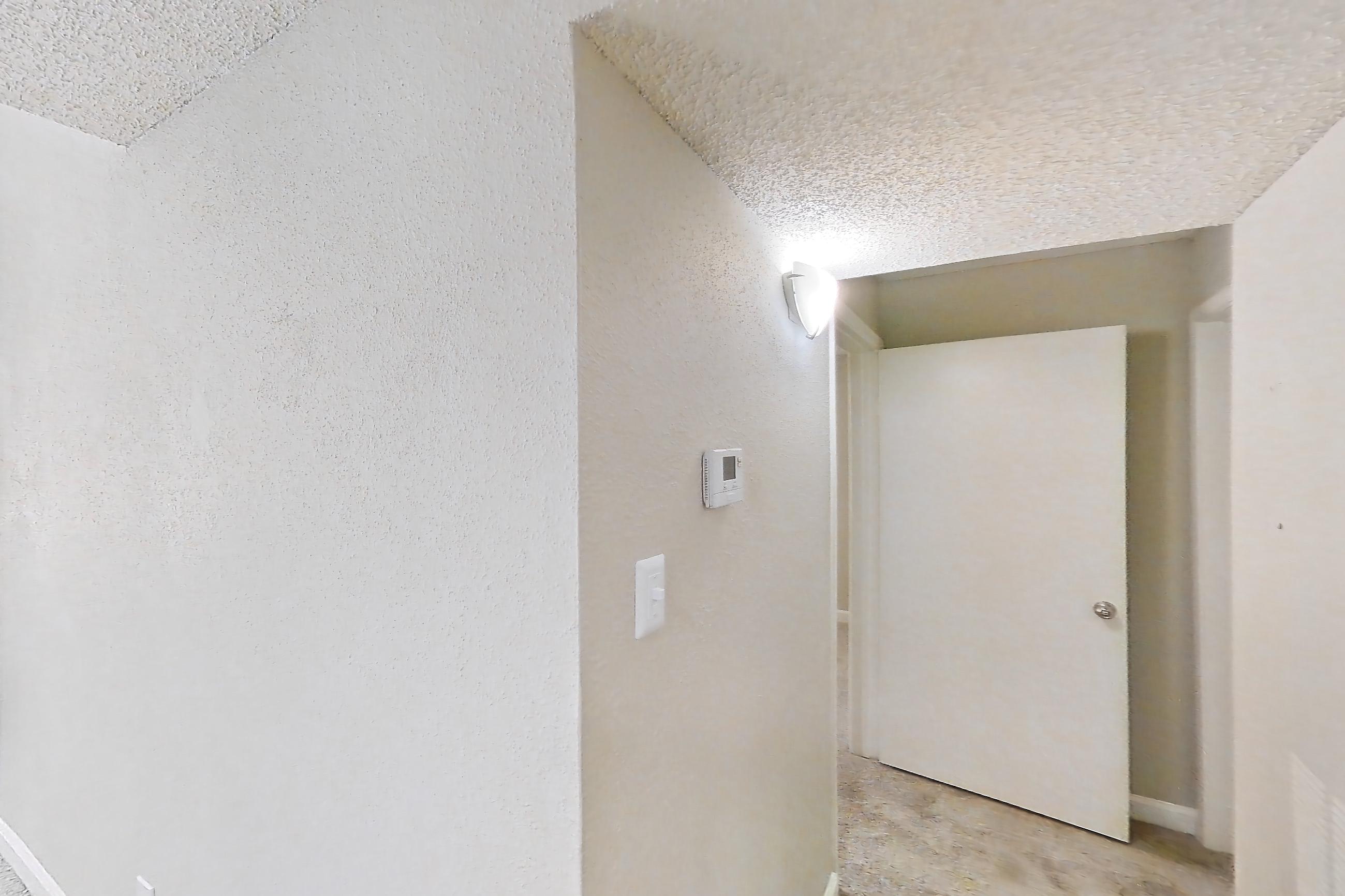 Kitchen entryway with electric range, light carpet, light stone countertops, light wood-finish flooring, oven/range, refrigerator, and stainless steel appliances, Apartment 0506 at Cortland at the Hammocks