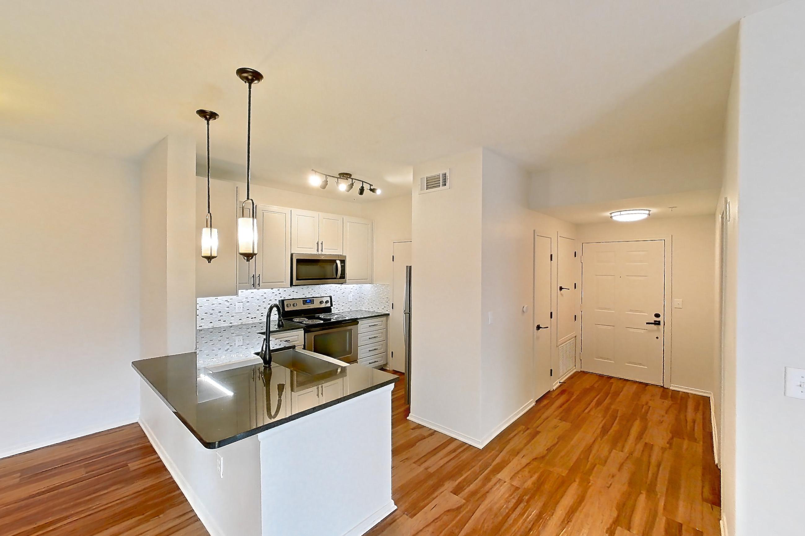 Living space with dark stone countertops, electric range, light wood-finish flooring, oven/range, and stainless steel appliances, Apartment 1418 at Cortland Grand River
