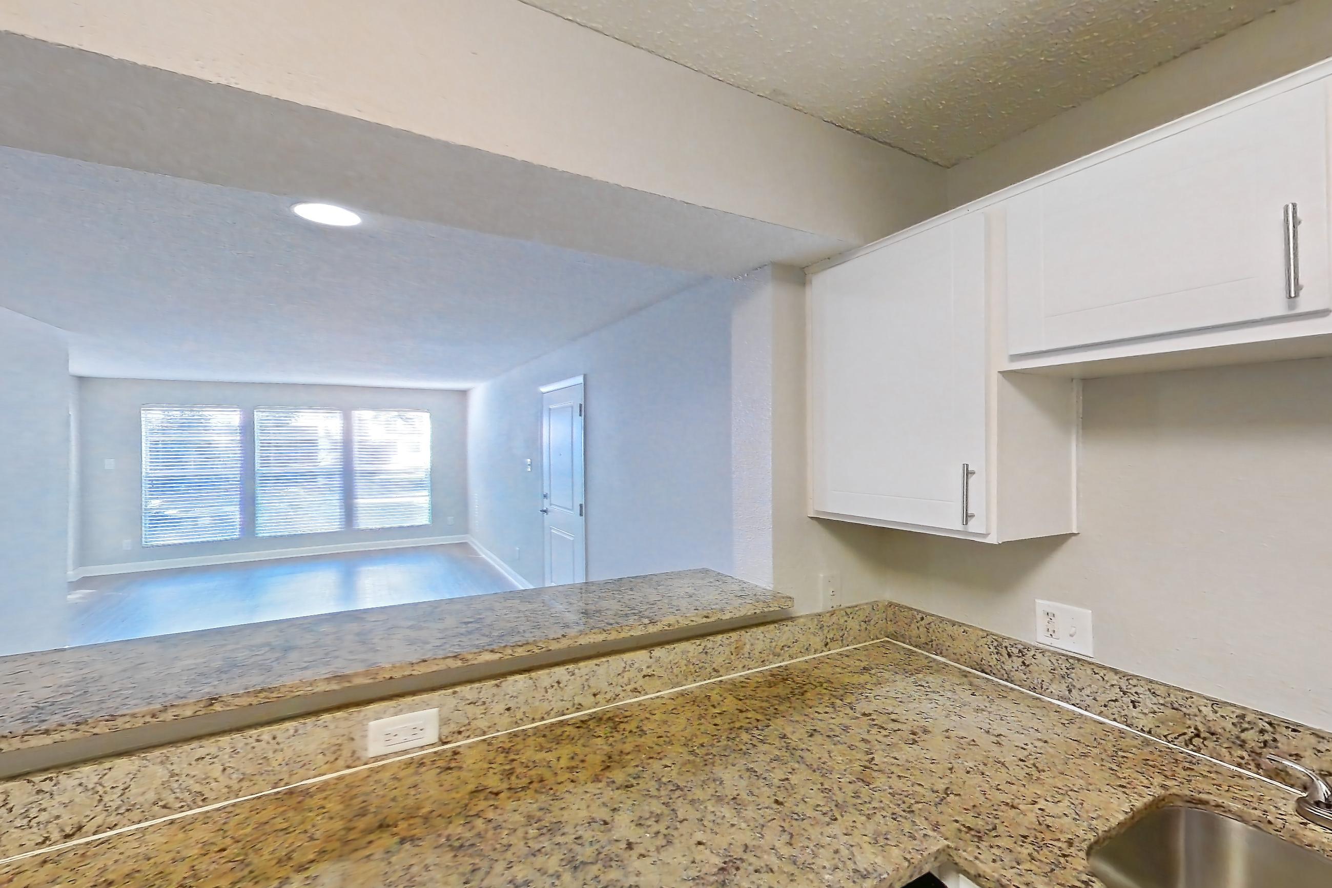 Kitchen with dark wood-finish flooring, dishwasher, electric range, light stone countertops, light wood-finish flooring, oven/range, range hood, refrigerator, and stainless steel appliances, Apartment 2421 at Cortland at the Hammocks