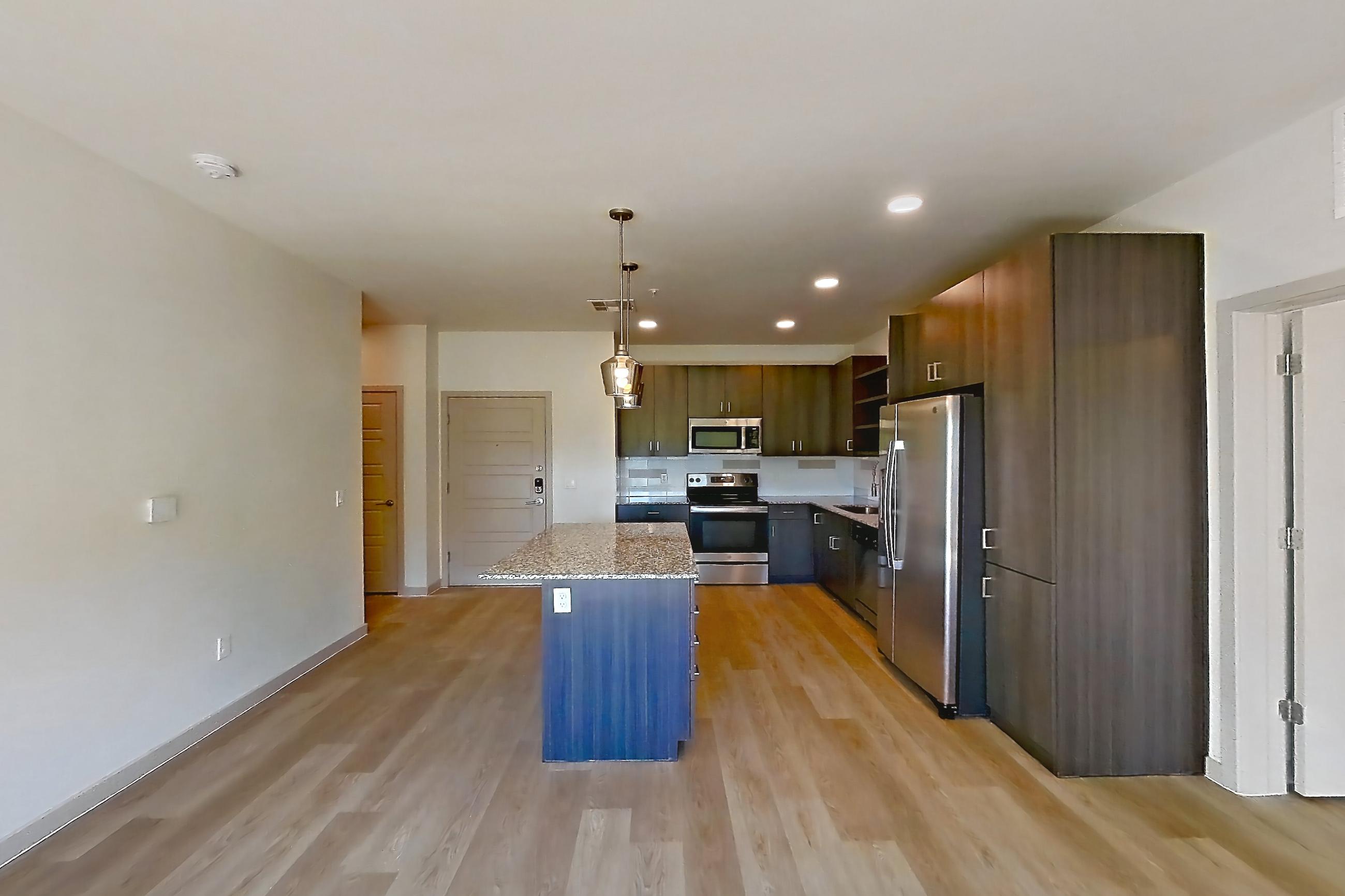 Living room with electric range, light countertops, light stone countertops, light wood-finish flooring, oven/range, refrigerator, stainless steel appliances, and water & ice dispenser, Apartment 1095 at Cortland at P83