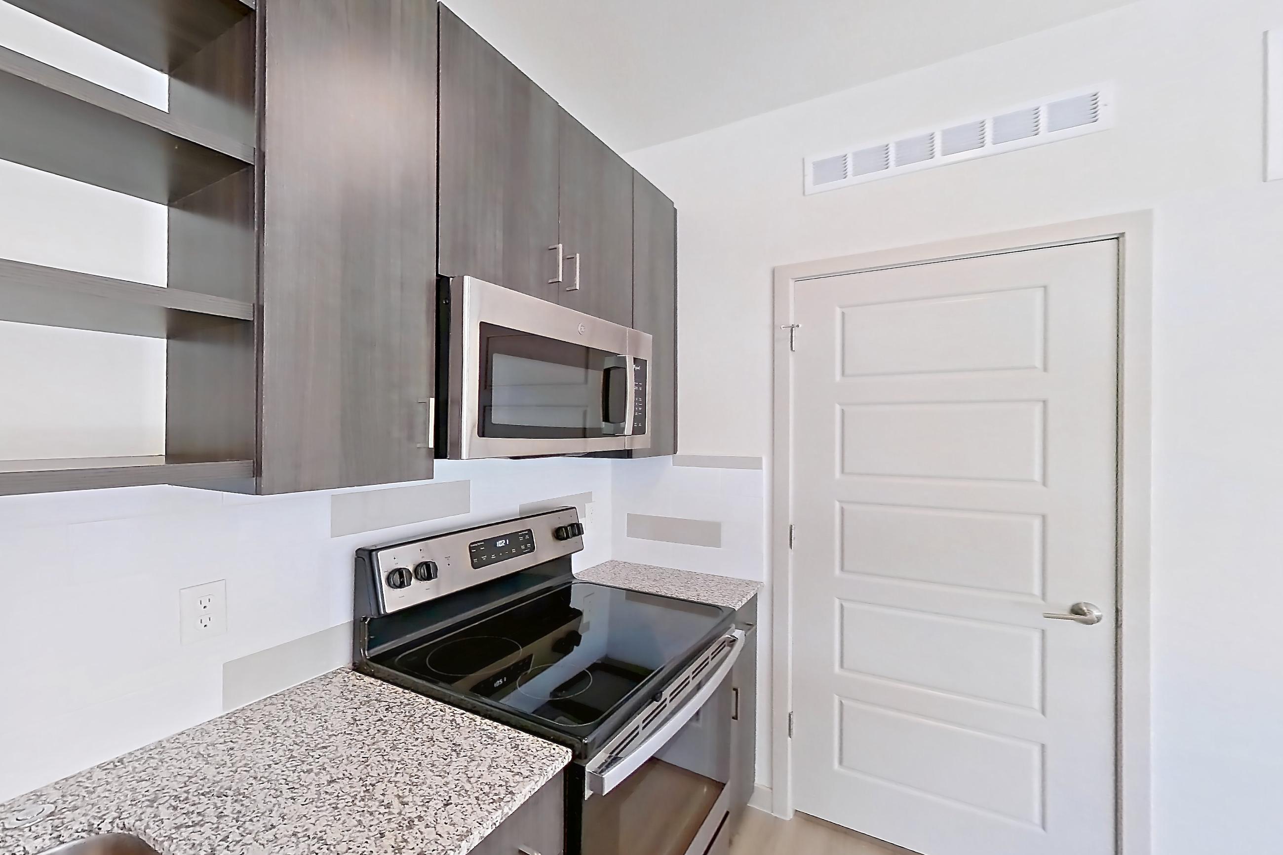 Kitchen with dishwasher, electric range, light stone countertops, light wood-finish flooring, oven/range, refrigerator, stainless steel appliances, and white appliances, Apartment 1097 at Cortland at P83