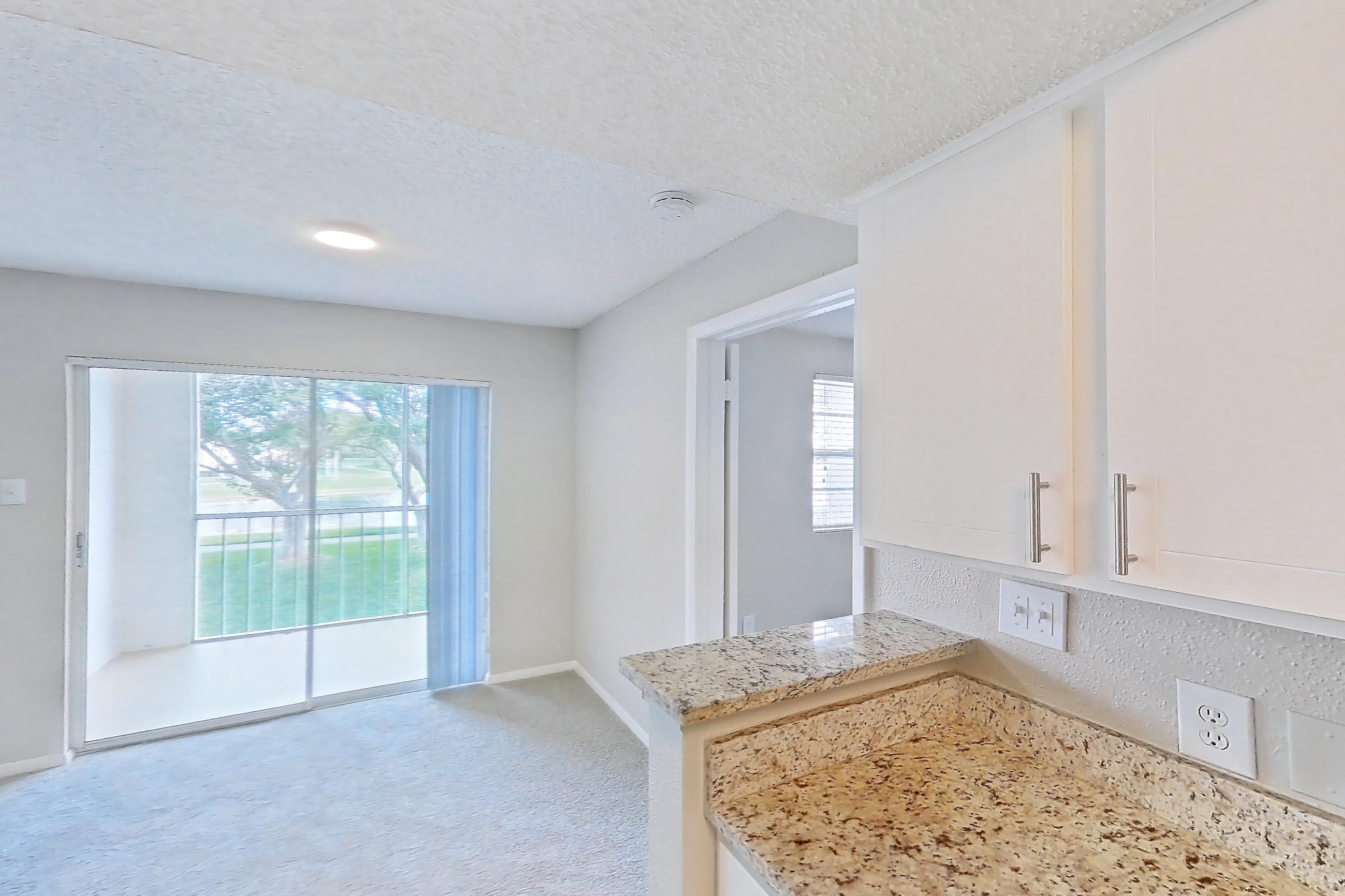 Kitchen with dishwasher, electric range, light carpet, light countertops, light stone countertops, light wood-finish flooring, oven/range, refrigerator, and stainless steel appliances, Apartment 1710 at Cortland at the Hammocks