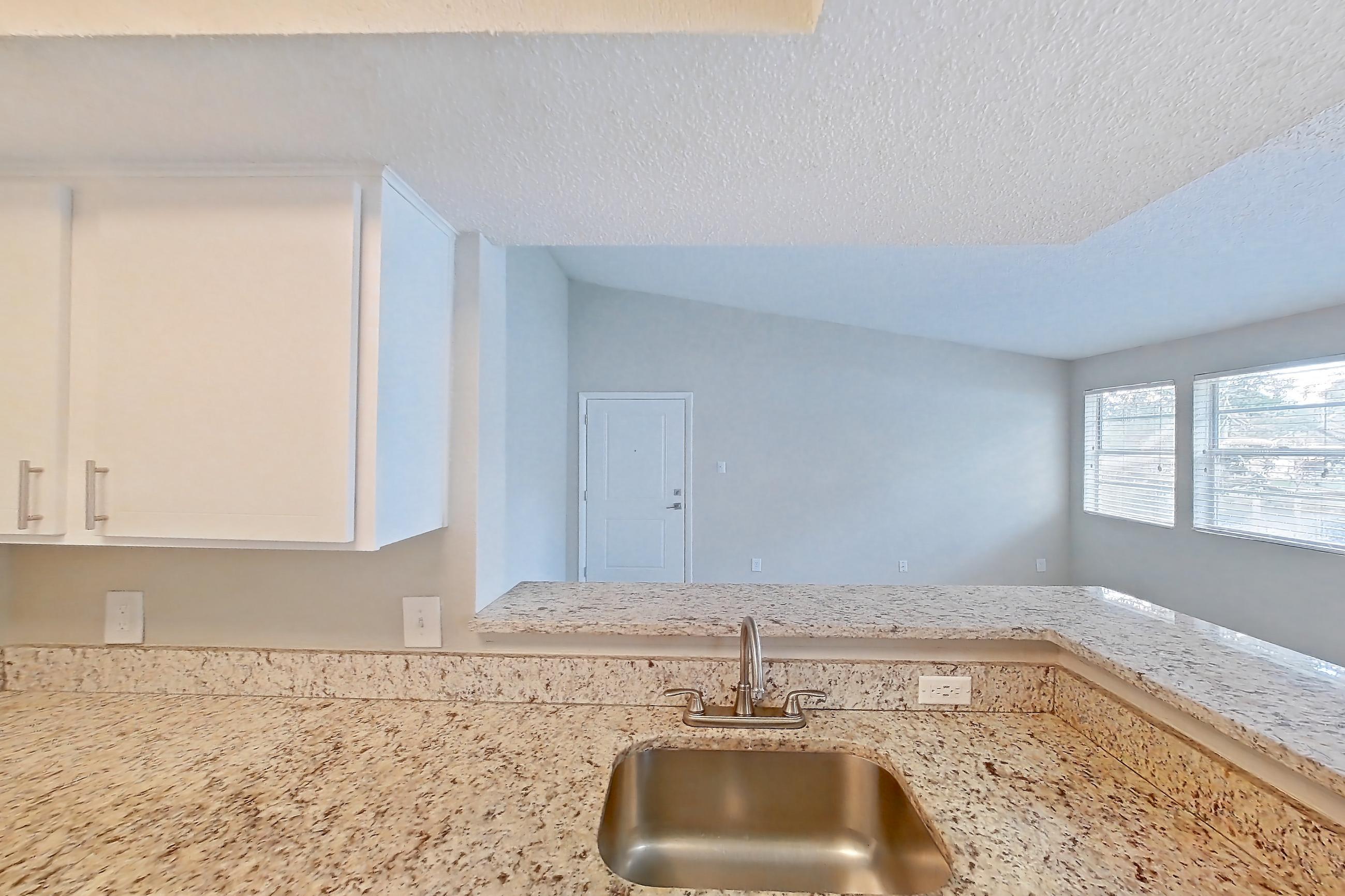 Kitchen with dishwasher, electric range, light carpet, light countertops, light stone countertops, light wood-finish flooring, oven/range, refrigerator, and stainless steel appliances, Apartment 1710 at Cortland at the Hammocks