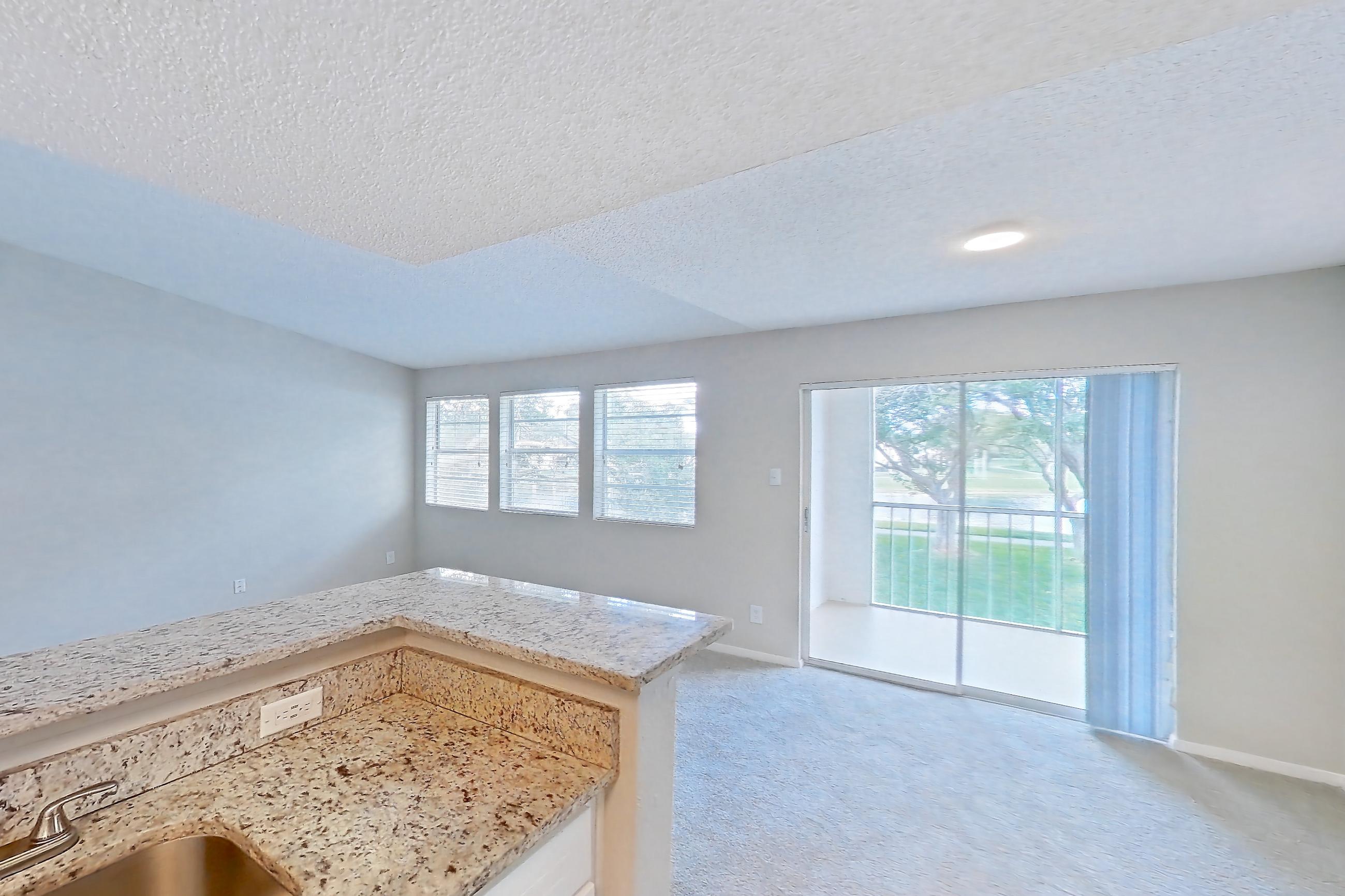 Kitchen with dishwasher, electric range, light carpet, light countertops, light stone countertops, light wood-finish flooring, oven/range, refrigerator, and stainless steel appliances, Apartment 1710 at Cortland at the Hammocks