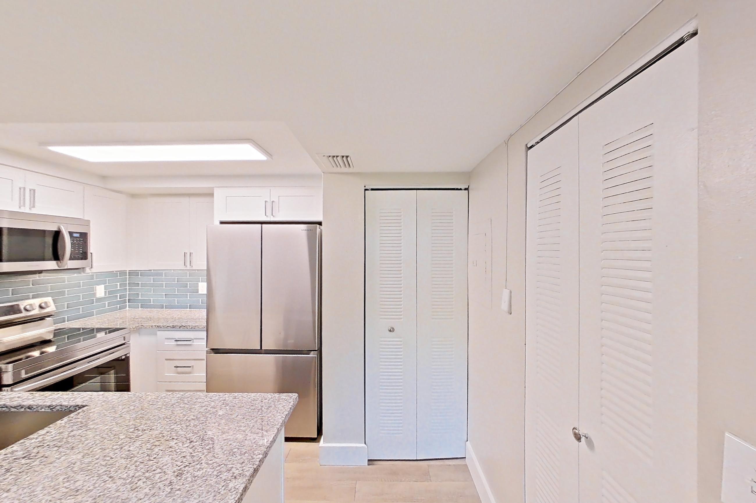Kitchen entryway with electric range, light stone countertops, light wood-finish flooring, oven/range, refrigerator, and stainless steel appliances, Apartment 01-017 at Cortland at the Hammocks