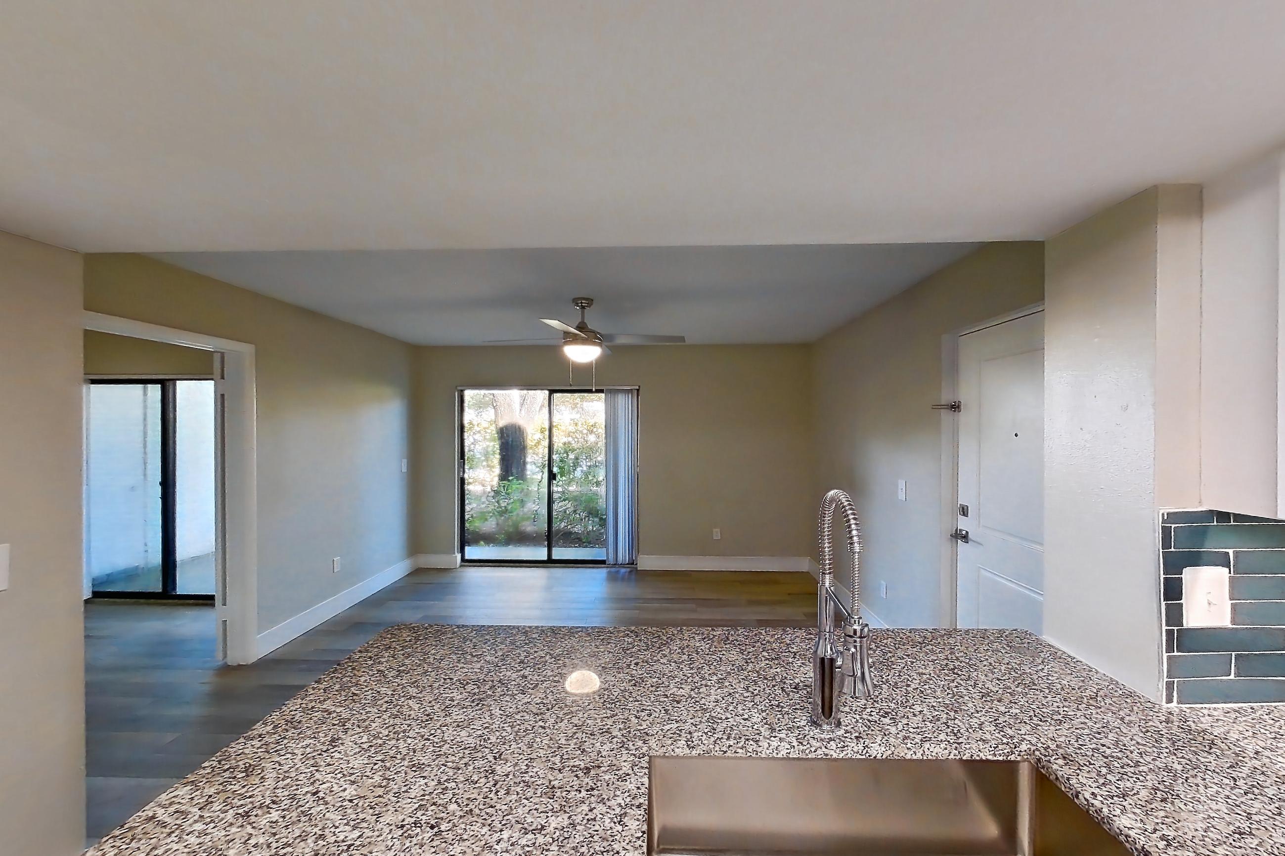 Kitchen with dishwasher, electric range, light countertops, light stone countertops, light wood-finish flooring, microwave, oven/range, refrigerator, and stainless steel appliances, Apartment 01-017 at Cortland at the Hammocks