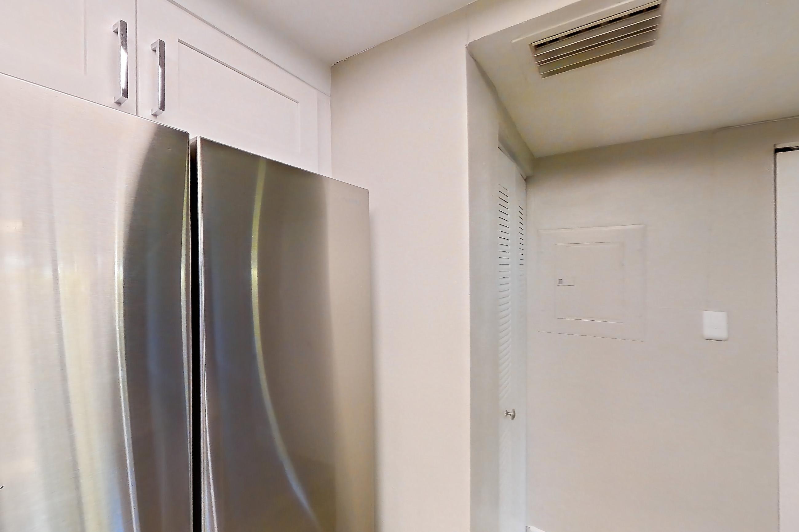 Kitchen with dishwasher, electric range, light countertops, light stone countertops, light wood-finish flooring, microwave, oven/range, refrigerator, and stainless steel appliances, Apartment 01-017 at Cortland at the Hammocks