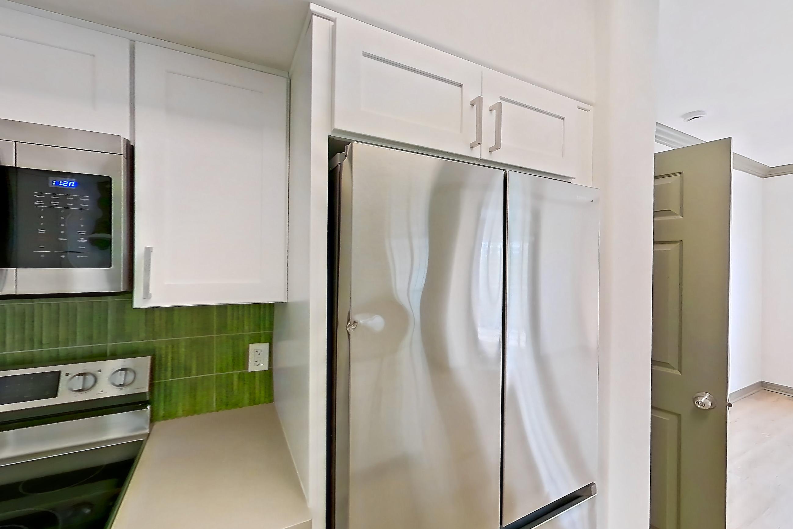 Kitchen with dishwasher, electric range, light countertops, light stone countertops, light wood-finish flooring, microwave, oven/range, refrigerator, and stainless steel appliances, Apartment 12309 at Cortland Lakecrest