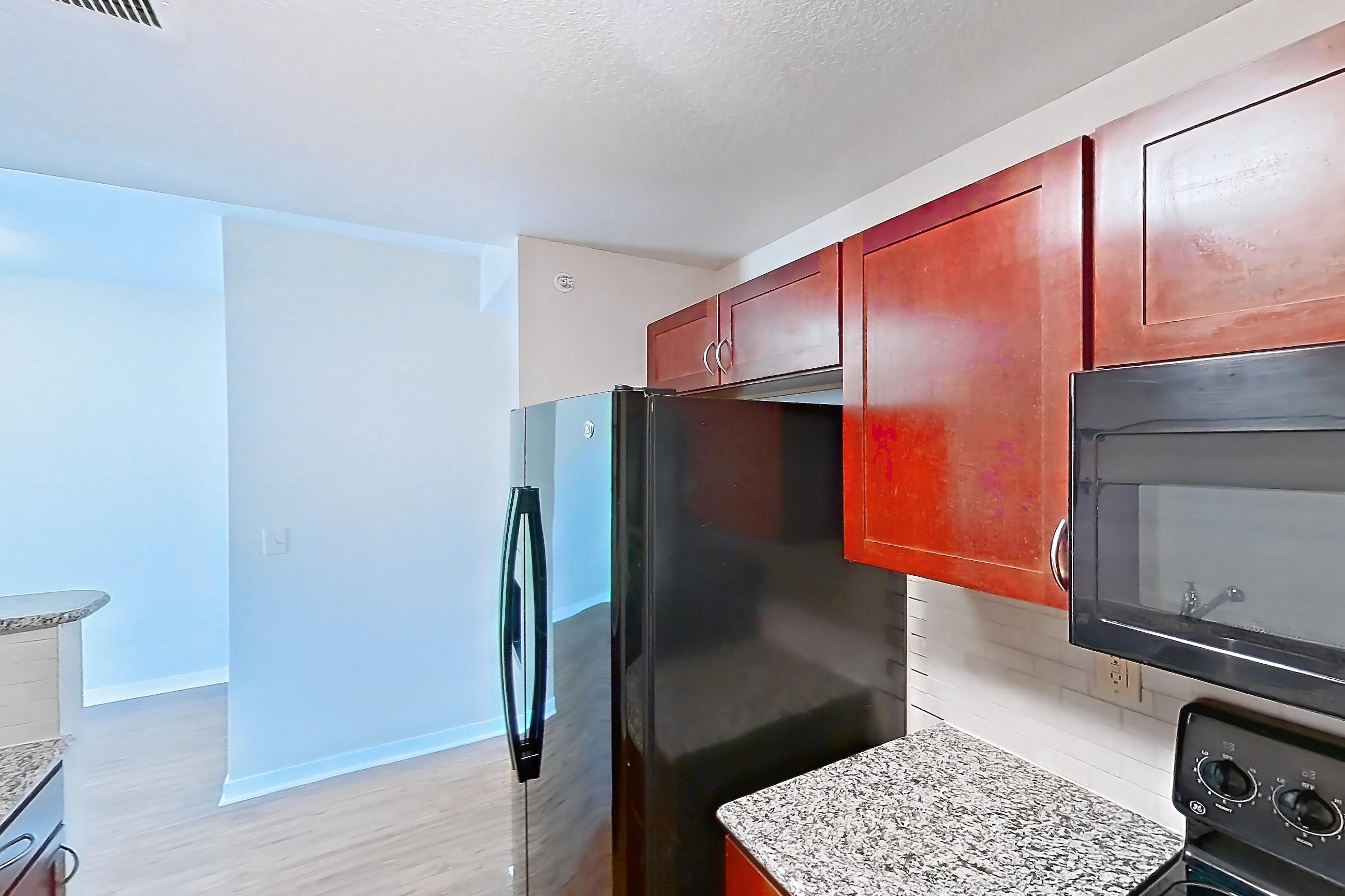 Kitchen with black appliances, dishwasher, electric range, light stone countertops, light wood-finish flooring, microwave, oven/range, and refrigerator, Apartment A-414-3B at Cortland Belmar