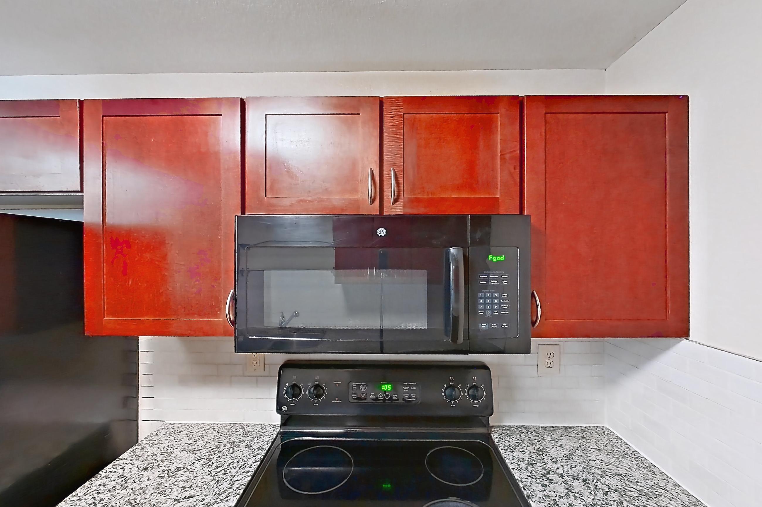 Kitchen with black appliances, dishwasher, electric range, light stone countertops, light wood-finish flooring, microwave, oven/range, and refrigerator, Apartment A-414-3B at Cortland Belmar