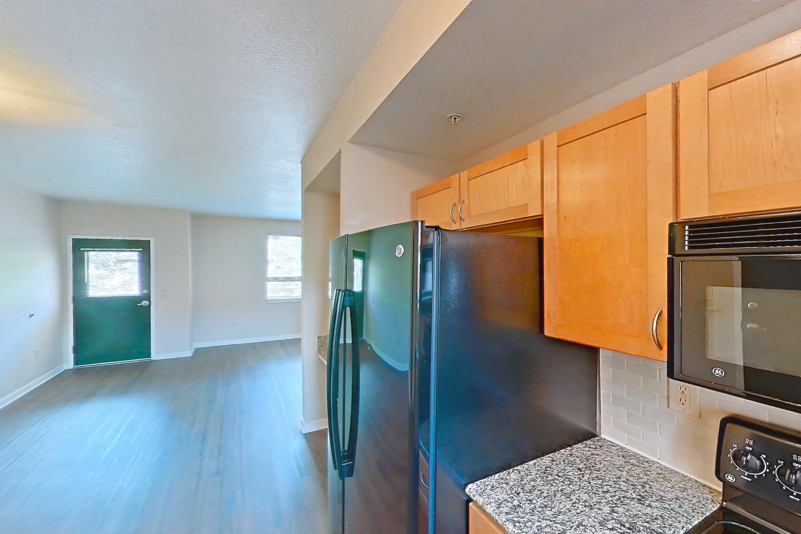 Kitchen with black appliances, dark wood-finish flooring, dishwasher, electric range, light stone countertops, microwave, oven/range, and refrigerator, Apartment A-464-2A at Cortland Belmar