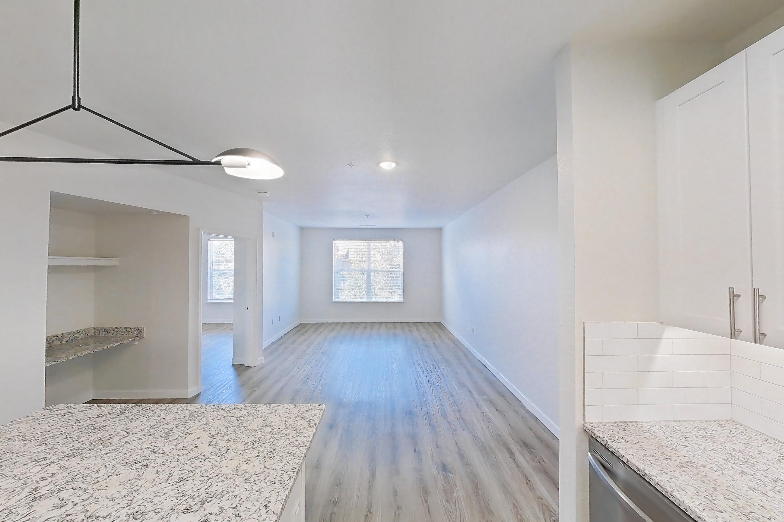 Kitchen with dishwasher, electric range, light countertops, light stone countertops, light wood-finish flooring, microwave, oven/range, refrigerator, and stainless steel appliances, Apartment A-212 at Cortland Belmar