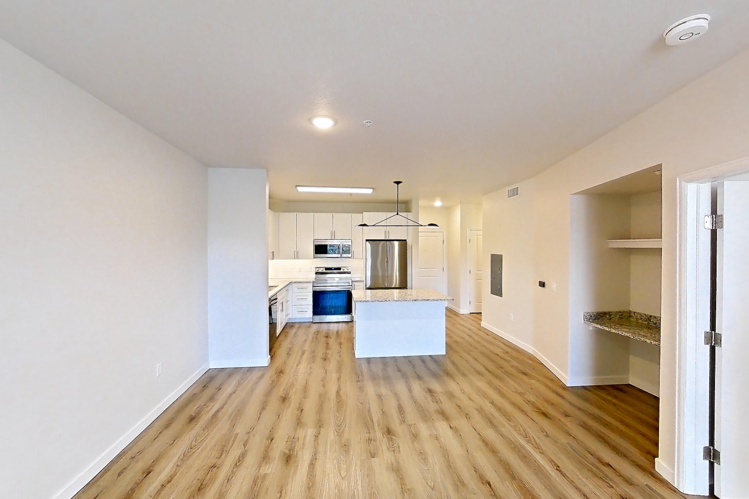 Living space with electric range, light stone countertops, light wood-finish flooring, oven/range, refrigerator, and stainless steel appliances, Apartment A-212 at Cortland Belmar