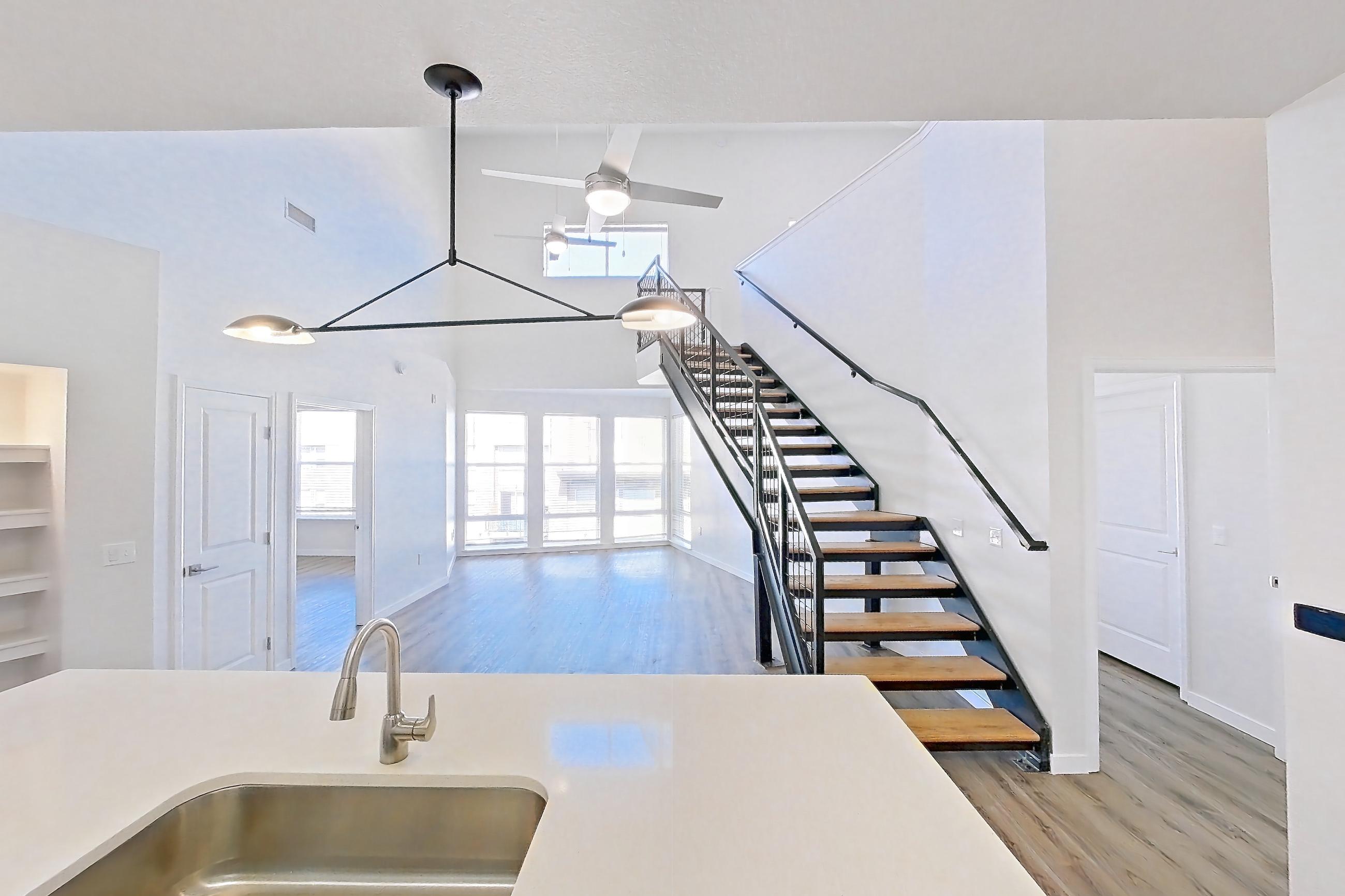 Kitchen with dishwasher, electric range, light countertops, light stone countertops, light wood-finish flooring, microwave, oven/range, refrigerator, and stainless steel appliances, Apartment C-440 at Cortland Belmar