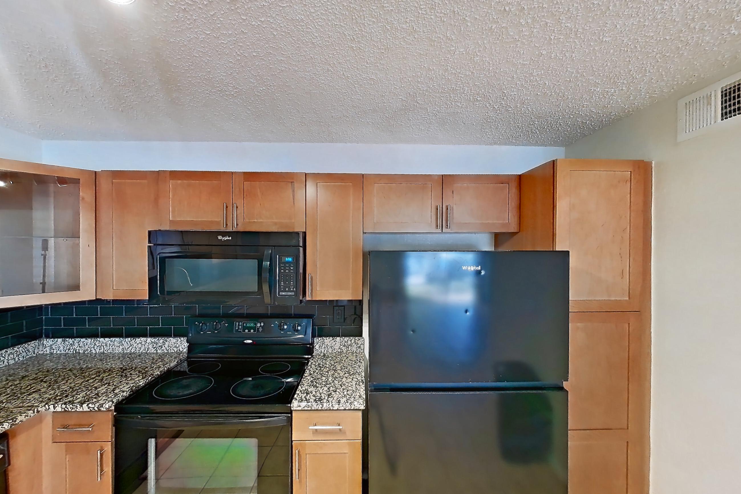 Kitchen with black appliances, dishwasher, electric range, light countertops, light stone countertops, light tile flooring, microwave, oven/range, and refrigerator, Apartment 185771 at Cortland Bayport