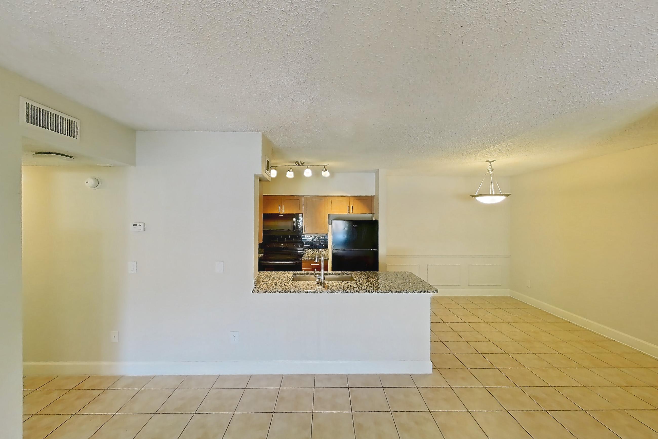 Living room with black appliances, dark stone countertops, electric range, light tile flooring, oven/range, and refrigerator, Apartment 565238 at Cortland Bayport