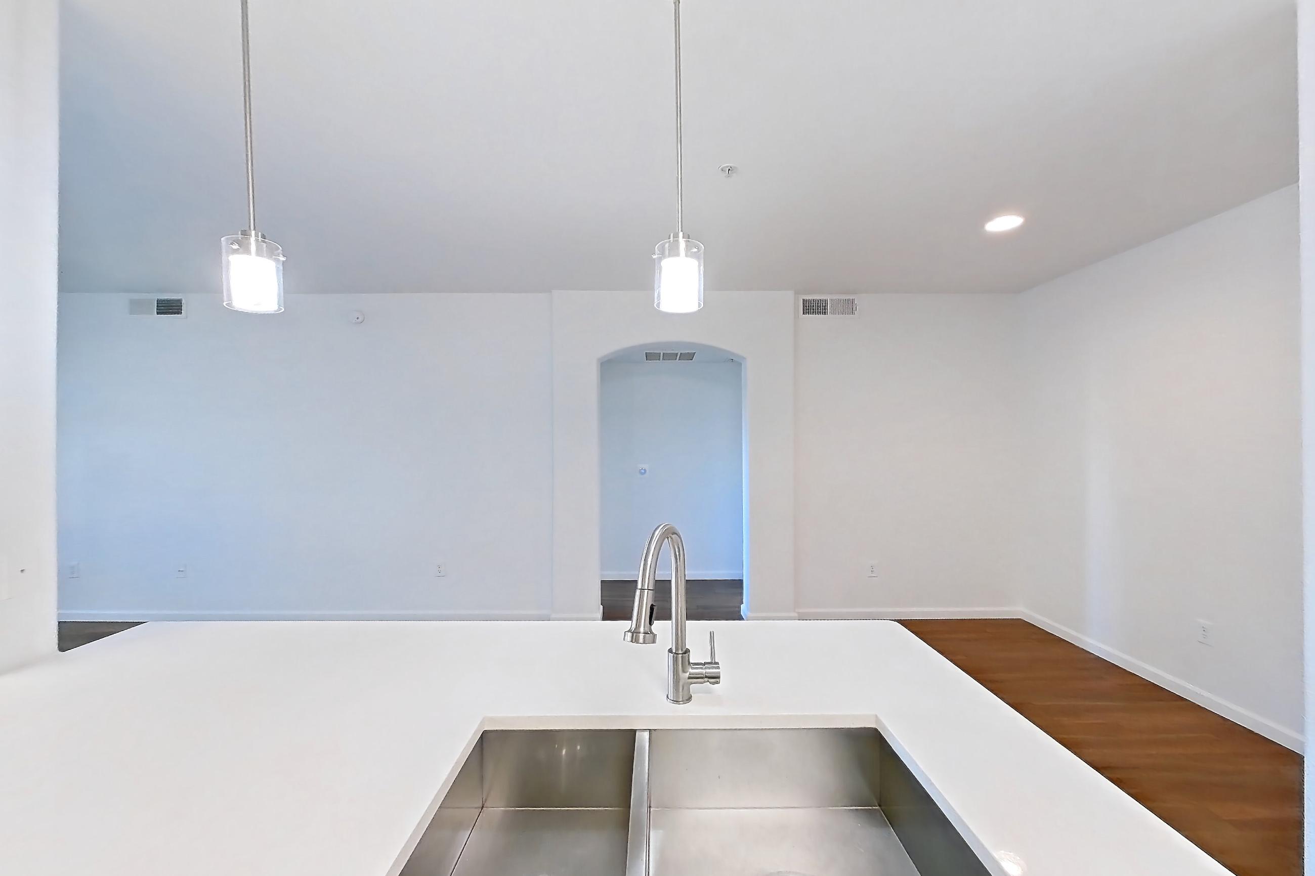 Kitchen with electric range, kitchen island, light countertops, light wood-finish flooring, microwave, oven/range, refrigerator, and stainless steel appliances, Apartment 1066 at Cortland South Mountain