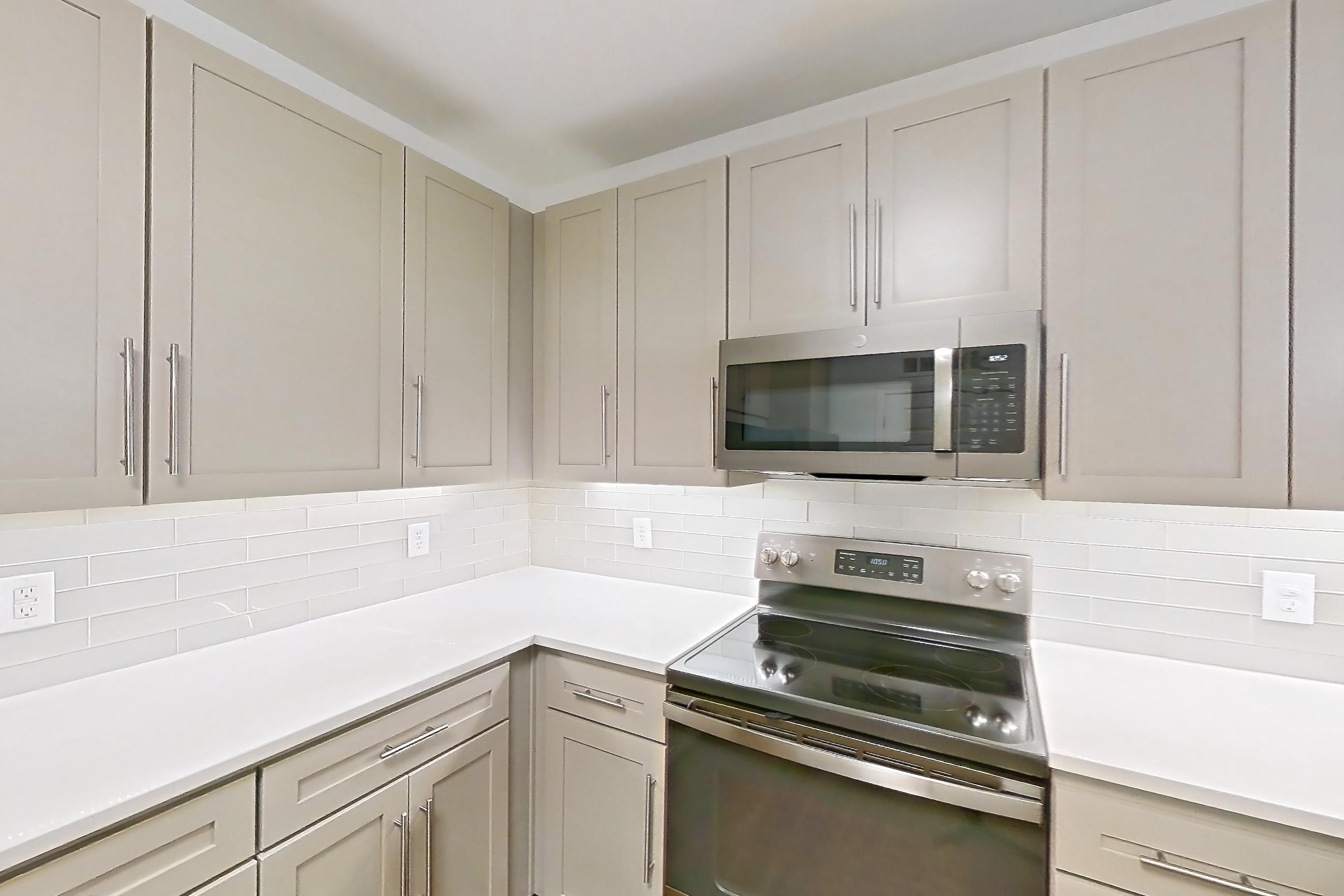 Kitchen with electric range, kitchen island, light countertops, light wood-finish flooring, microwave, oven/range, refrigerator, and stainless steel appliances, Apartment 1066 at Cortland South Mountain