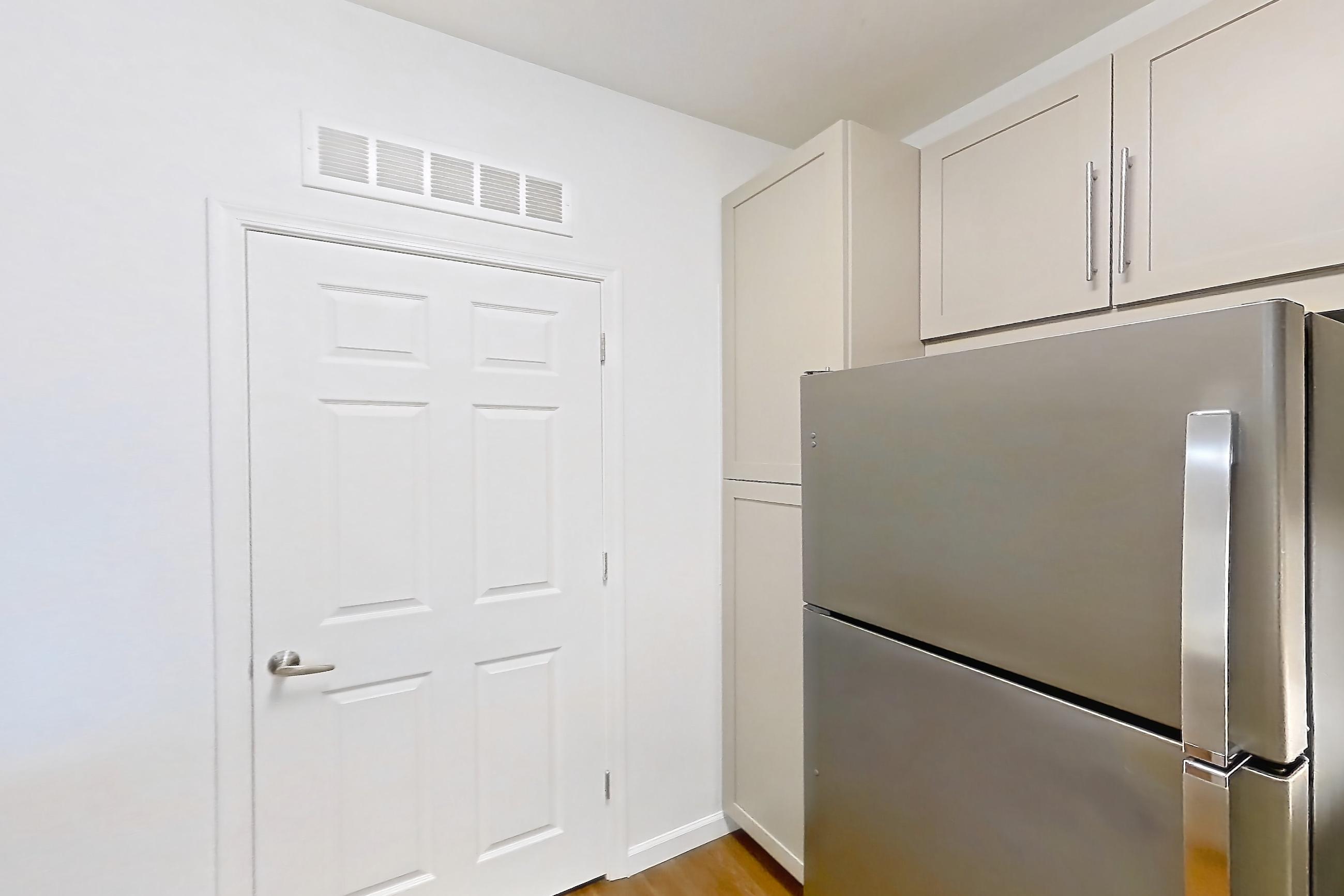 Kitchen with electric range, kitchen island, light countertops, light wood-finish flooring, microwave, oven/range, refrigerator, and stainless steel appliances, Apartment 1066 at Cortland South Mountain