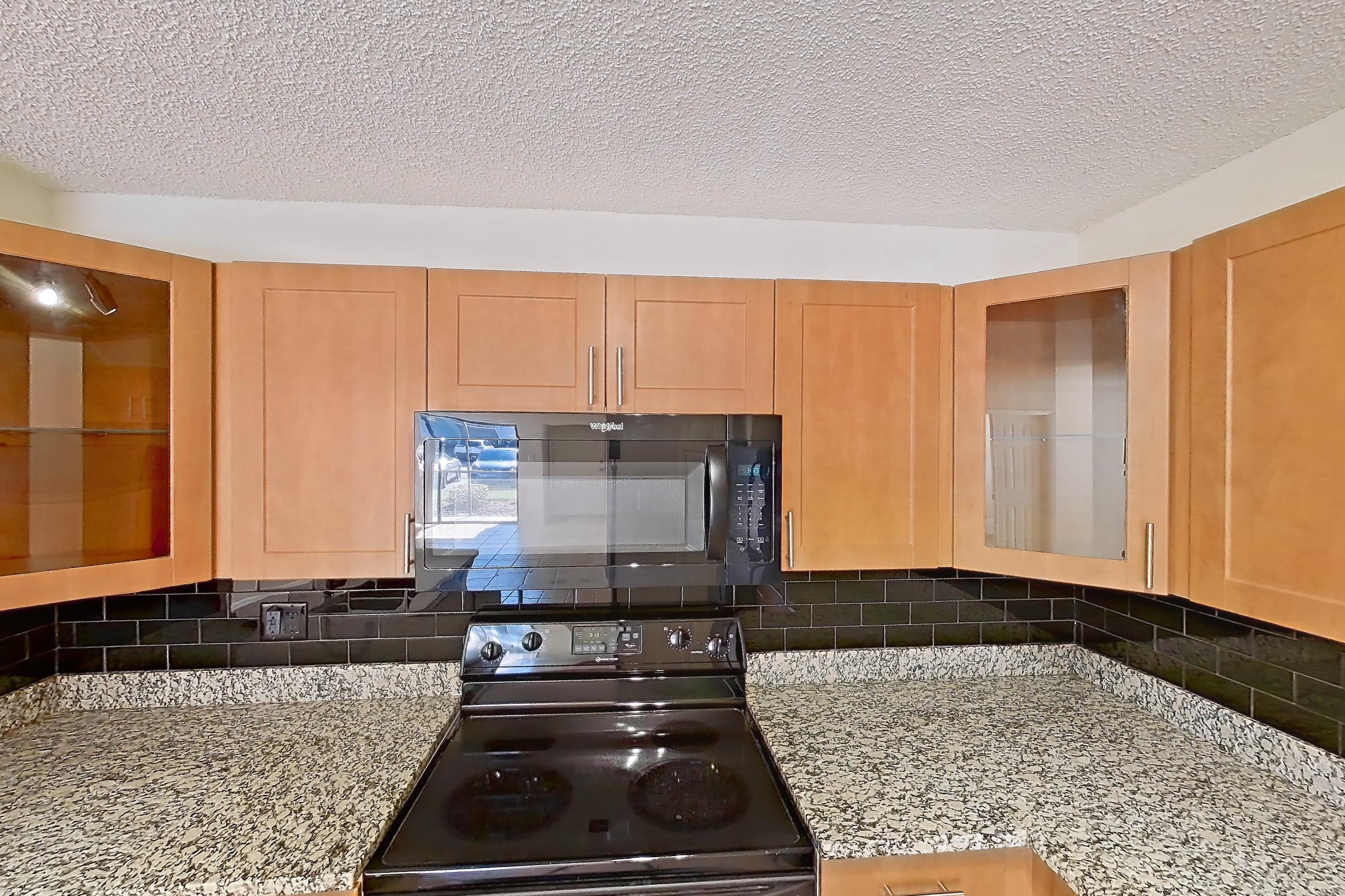 Kitchen with black appliances, dishwasher, electric range, light stone countertops, light tile flooring, microwave, oven/range, and refrigerator, Apartment 065574 at Cortland Bayport