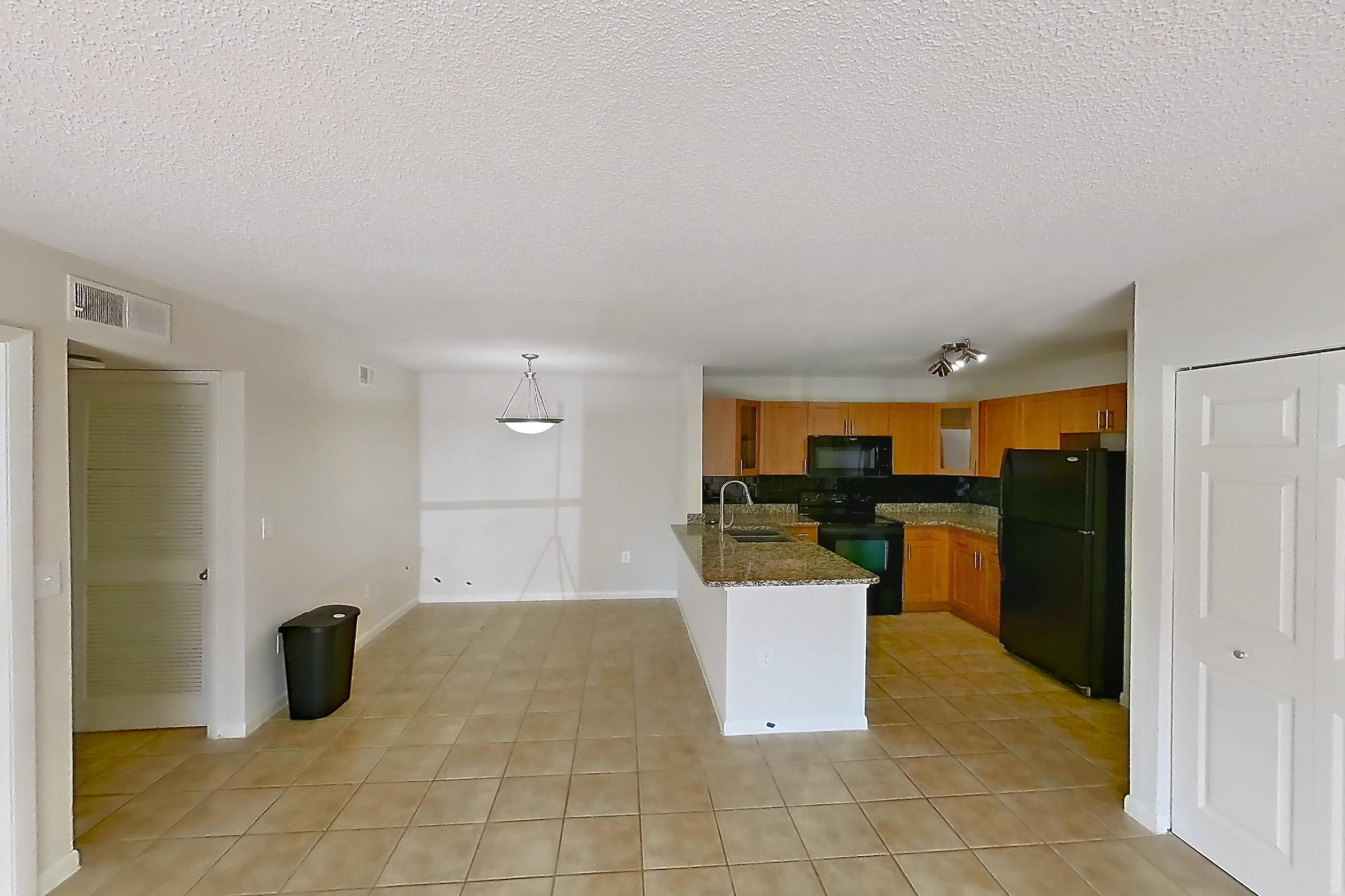 Living room with black appliances, dark stone countertops, electric range, light tile flooring, oven/range, and refrigerator, Apartment 065574 at Cortland Bayport